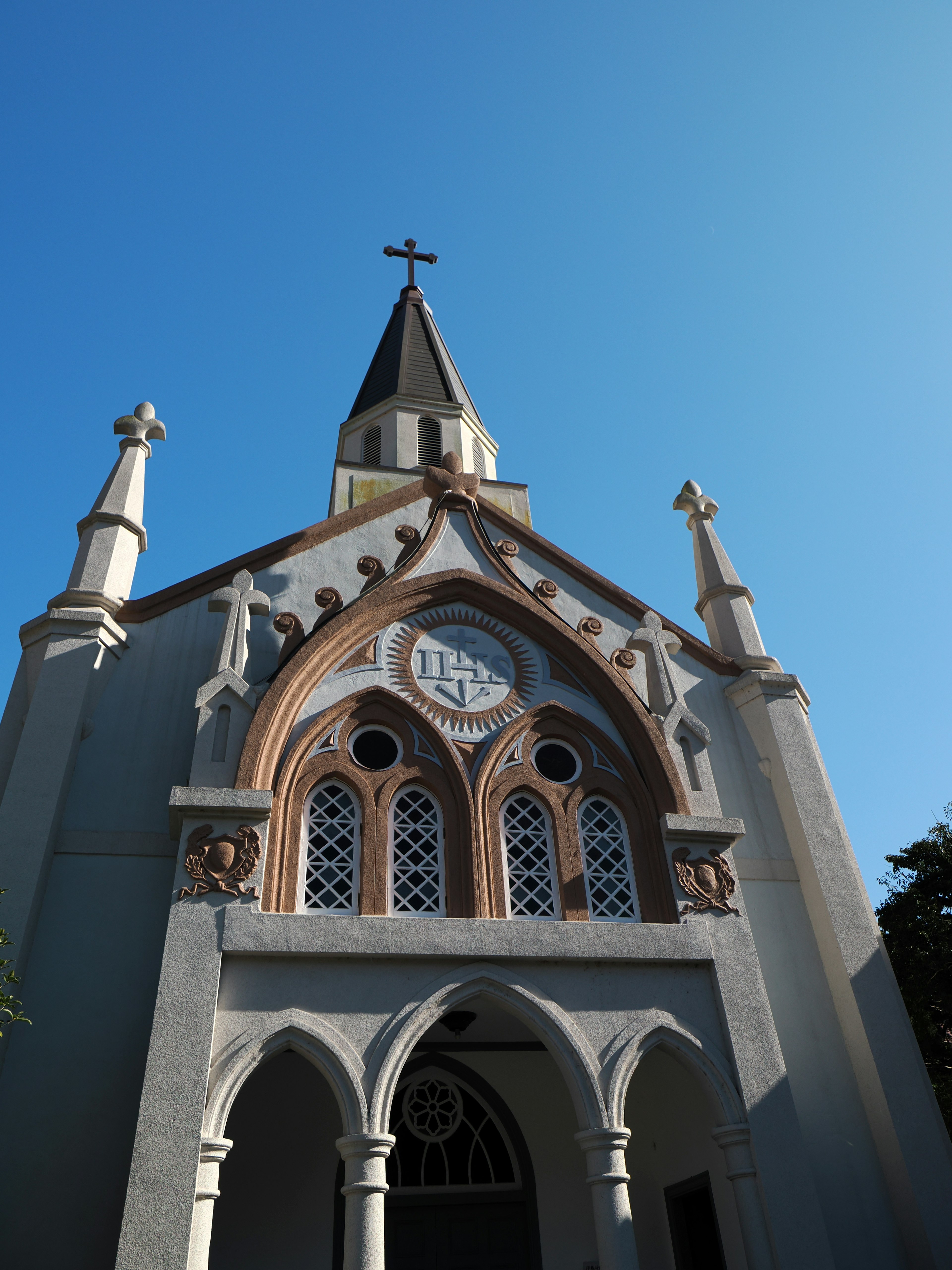 Bella facciata di chiesa contro un cielo blu con un alto campanile e archi decorativi