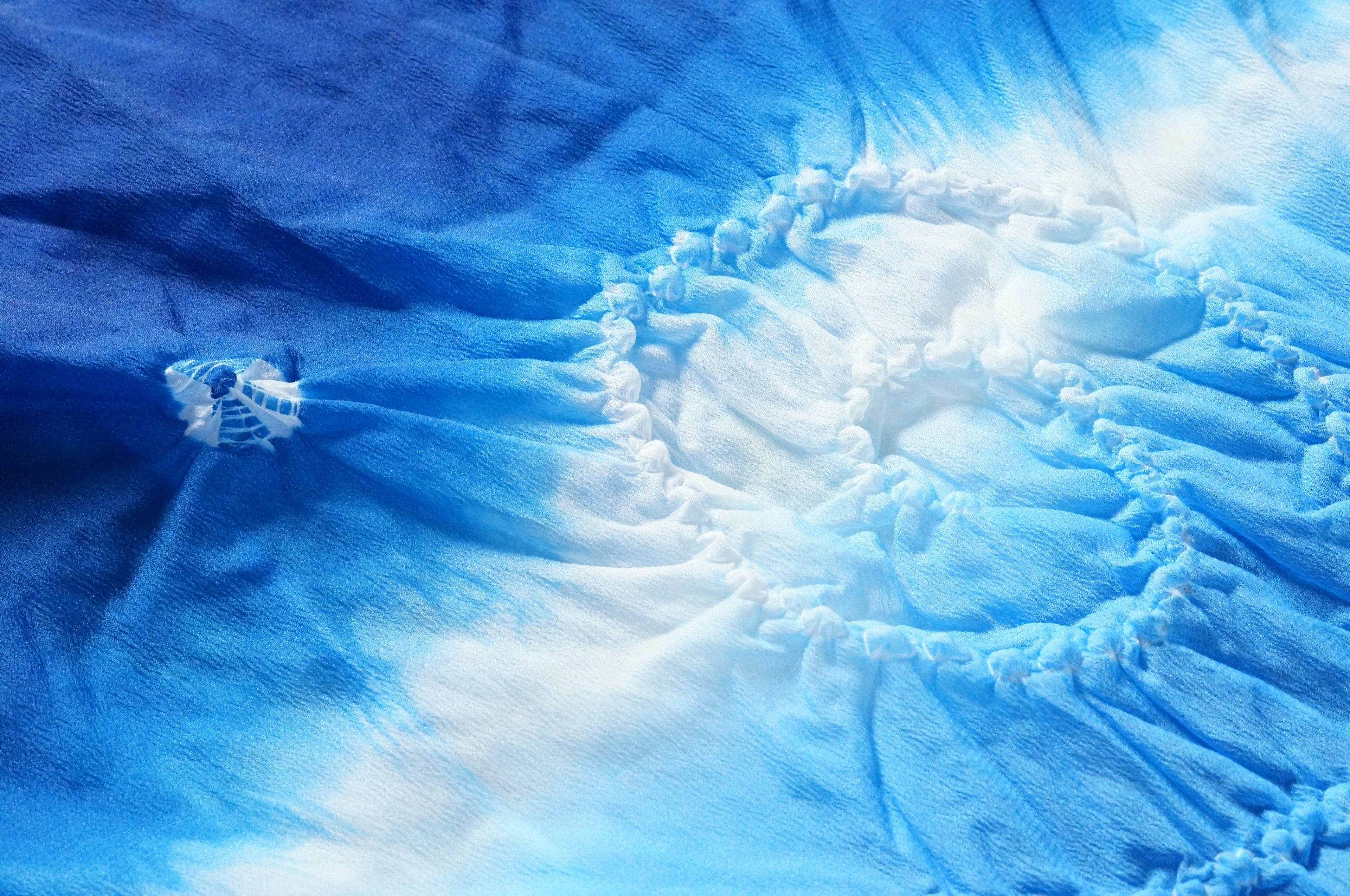 Close-up of blue tie-dye fabric featuring a spiral pattern and soft texture