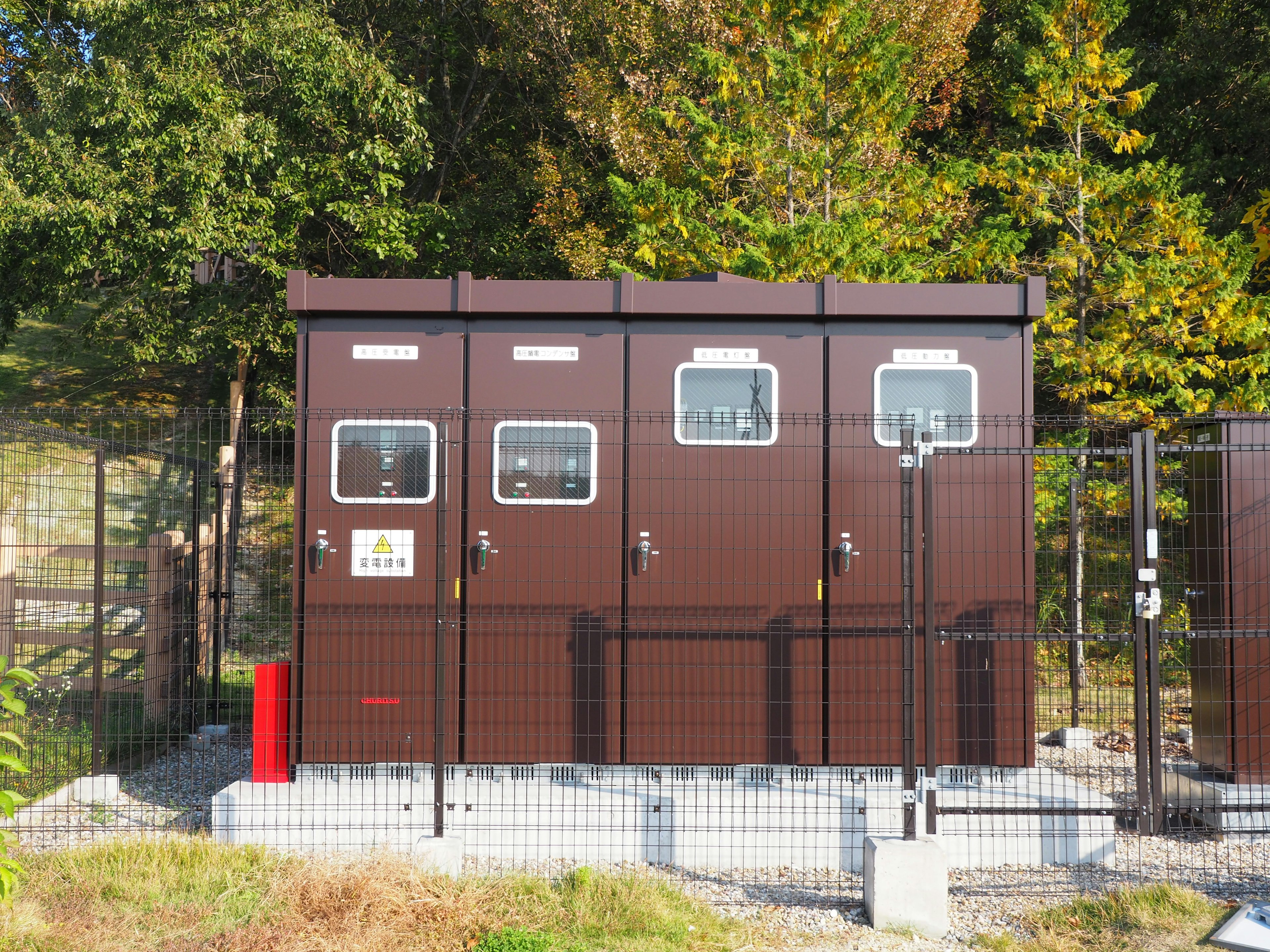 Image of three brown utility cabins surrounded by green trees