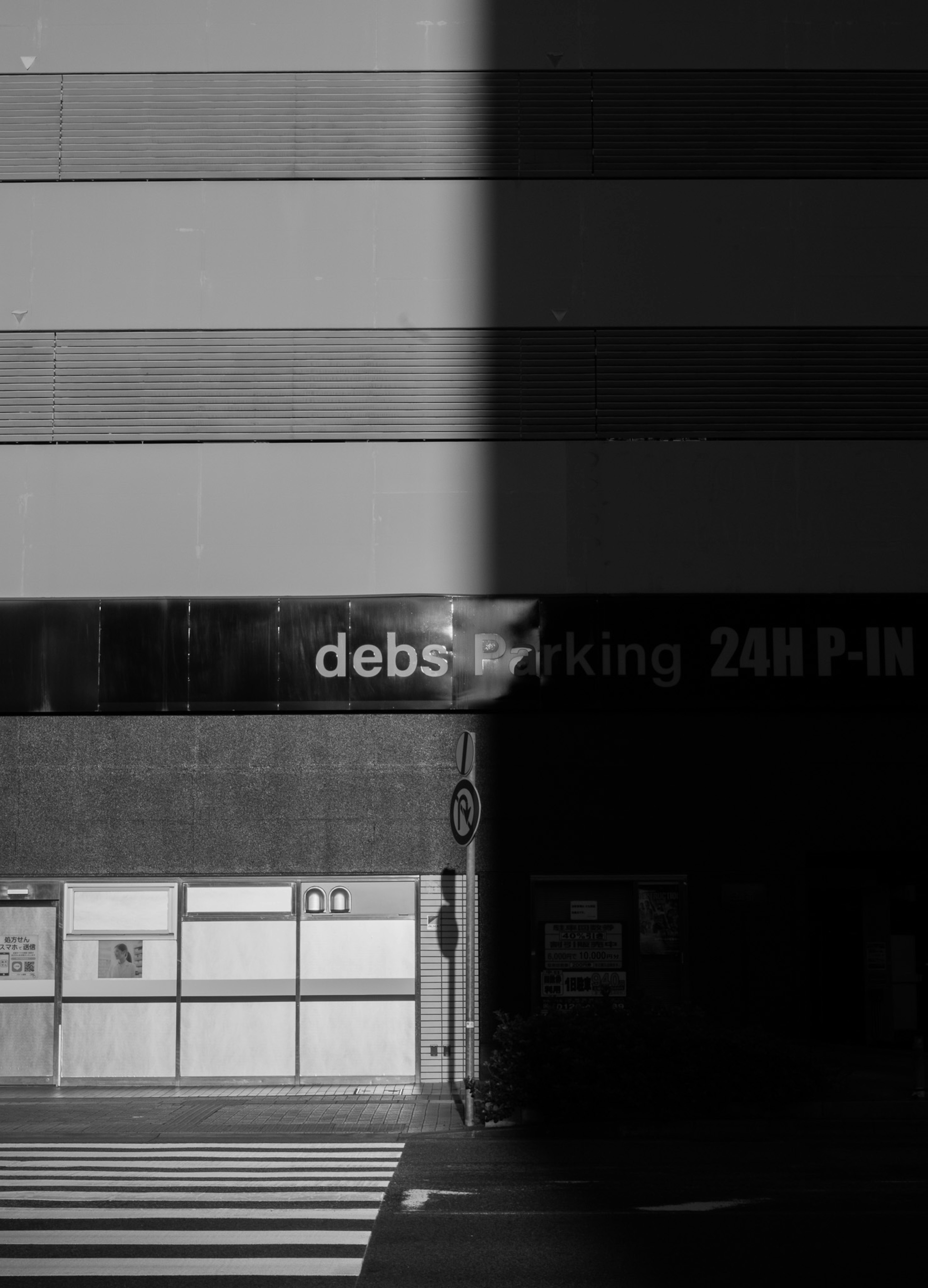 대비가 강한 흑백 이미지의 건물 외관과 debs parking 24H P-IN 간판