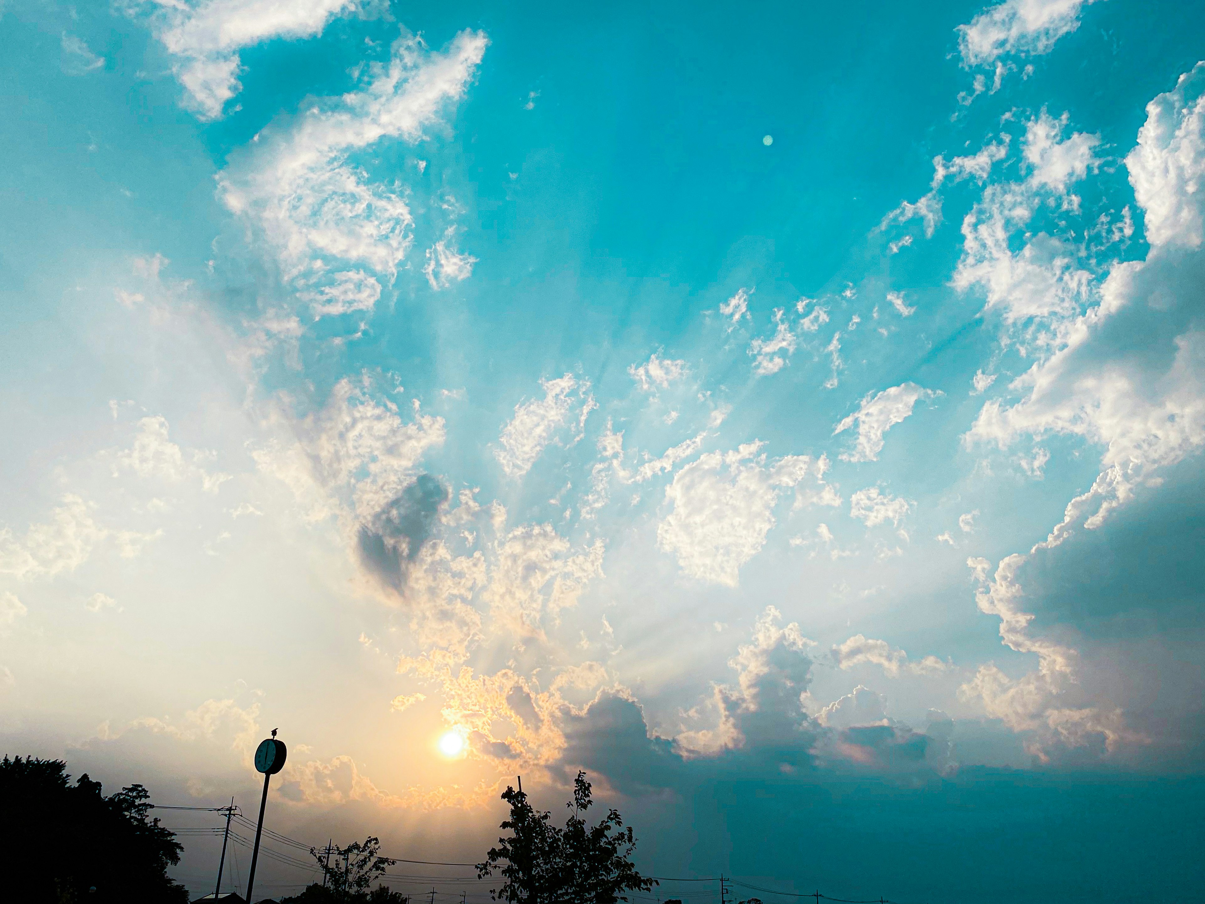 A scenic view of the sun rising behind clouds with rays of light