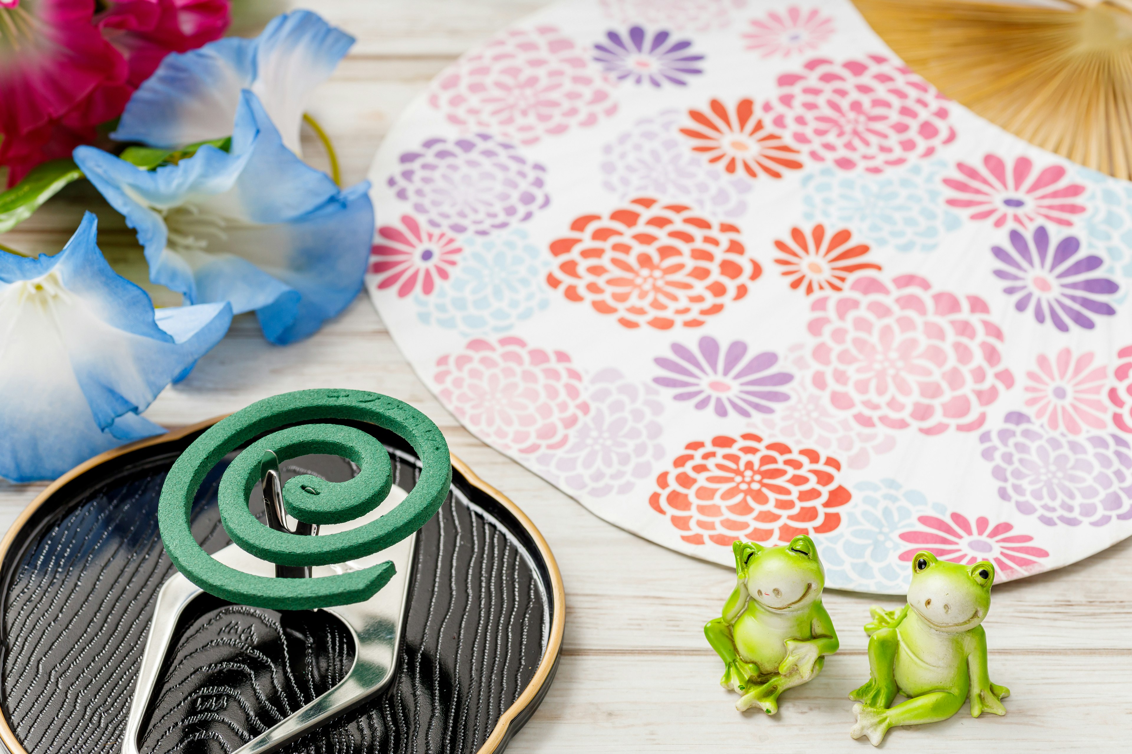 Table with colorful floral patterned fan and frog figurines