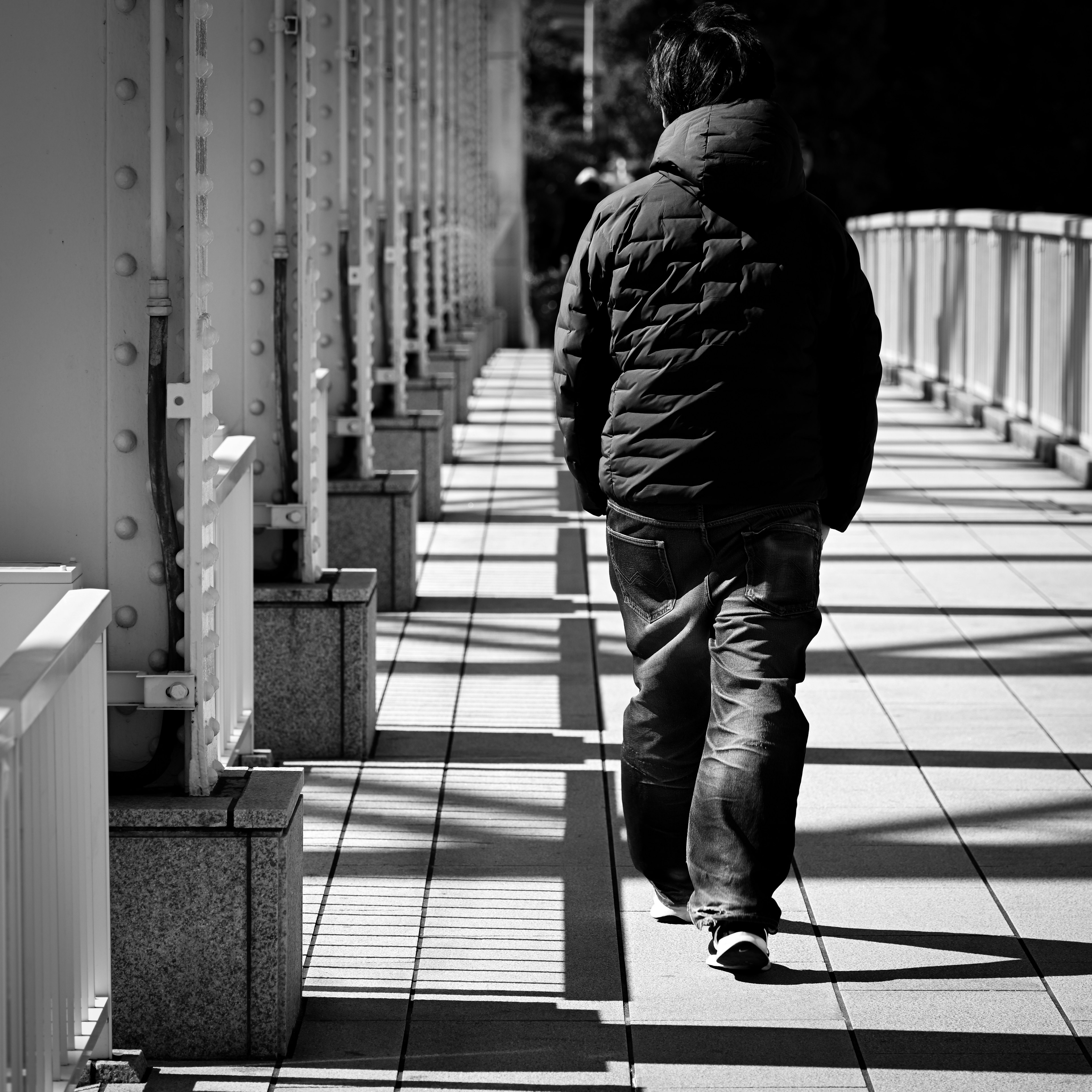 Un hombre caminando sobre un puente en una foto en blanco y negro