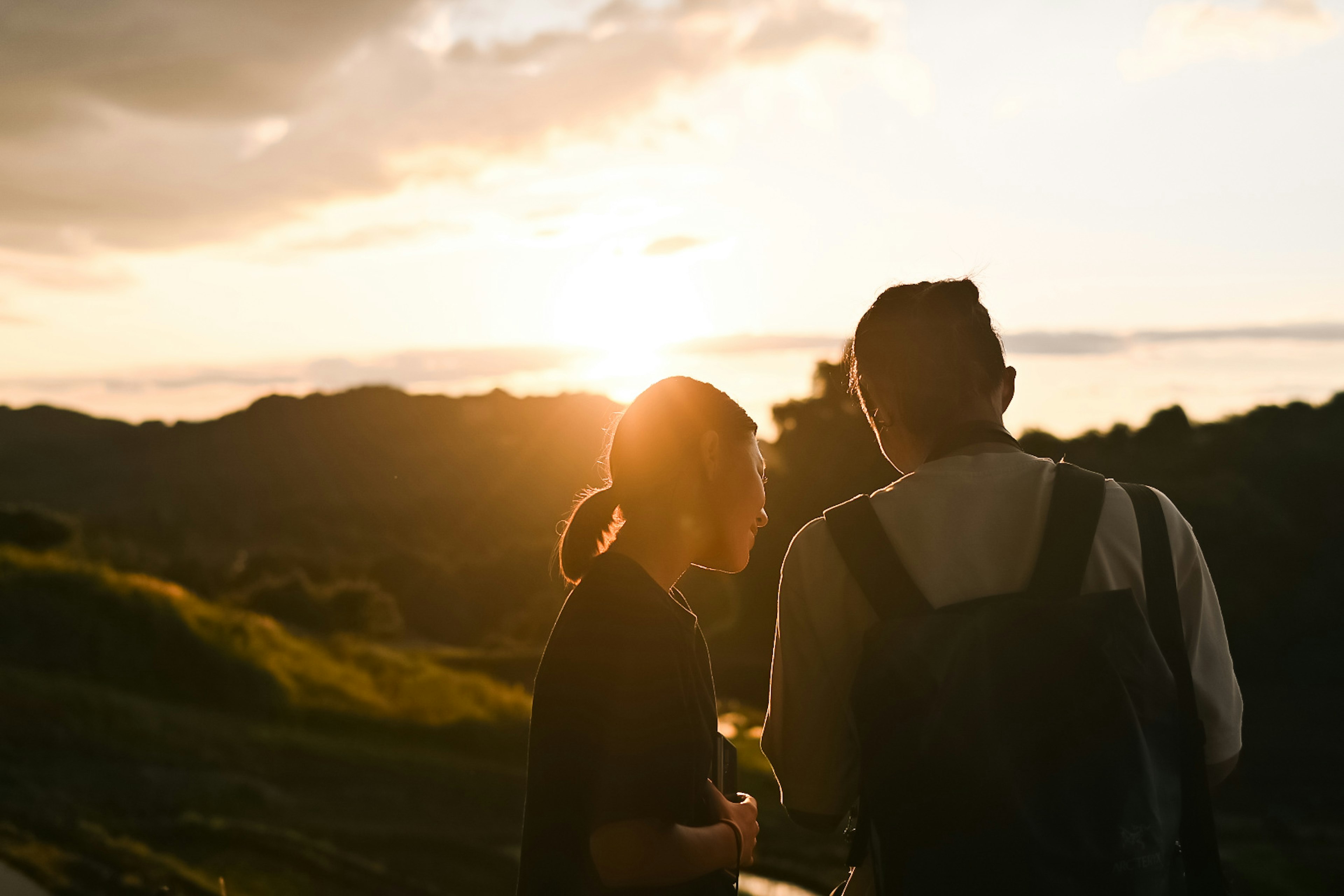 Dos personas conversando con un atardecer de fondo