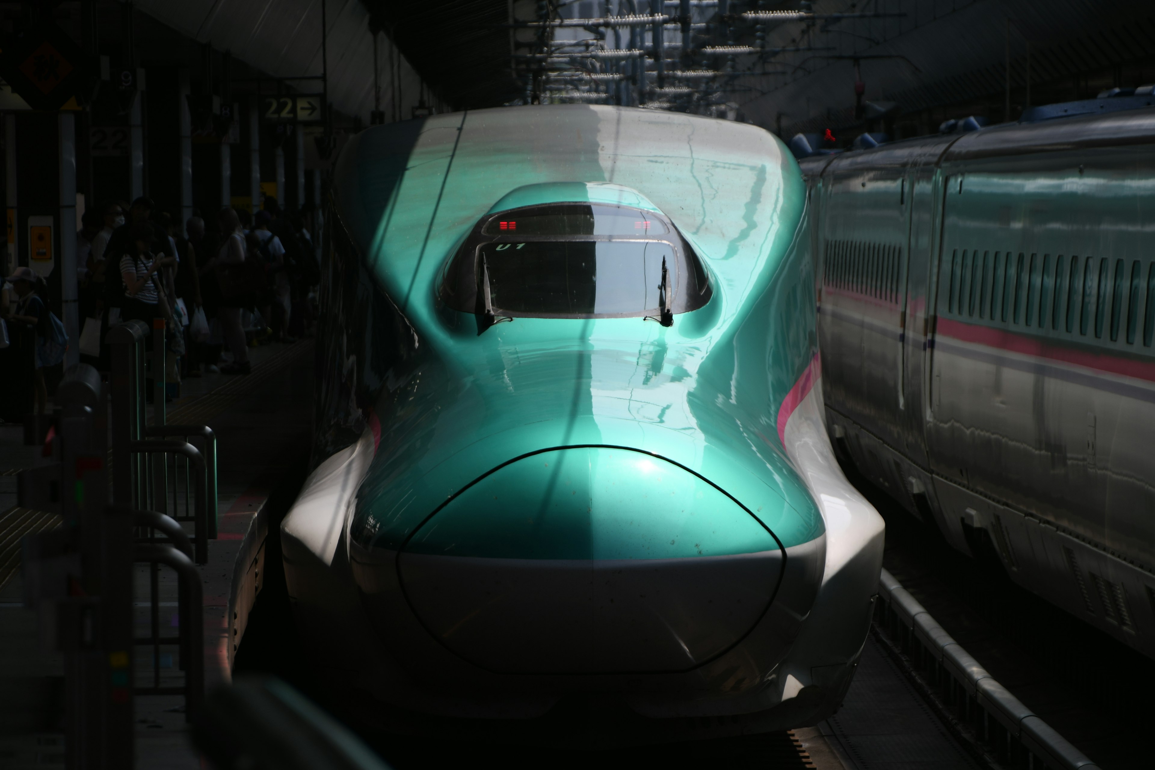 Un treno Shinkansen verde distintivo in stazione con design elegante