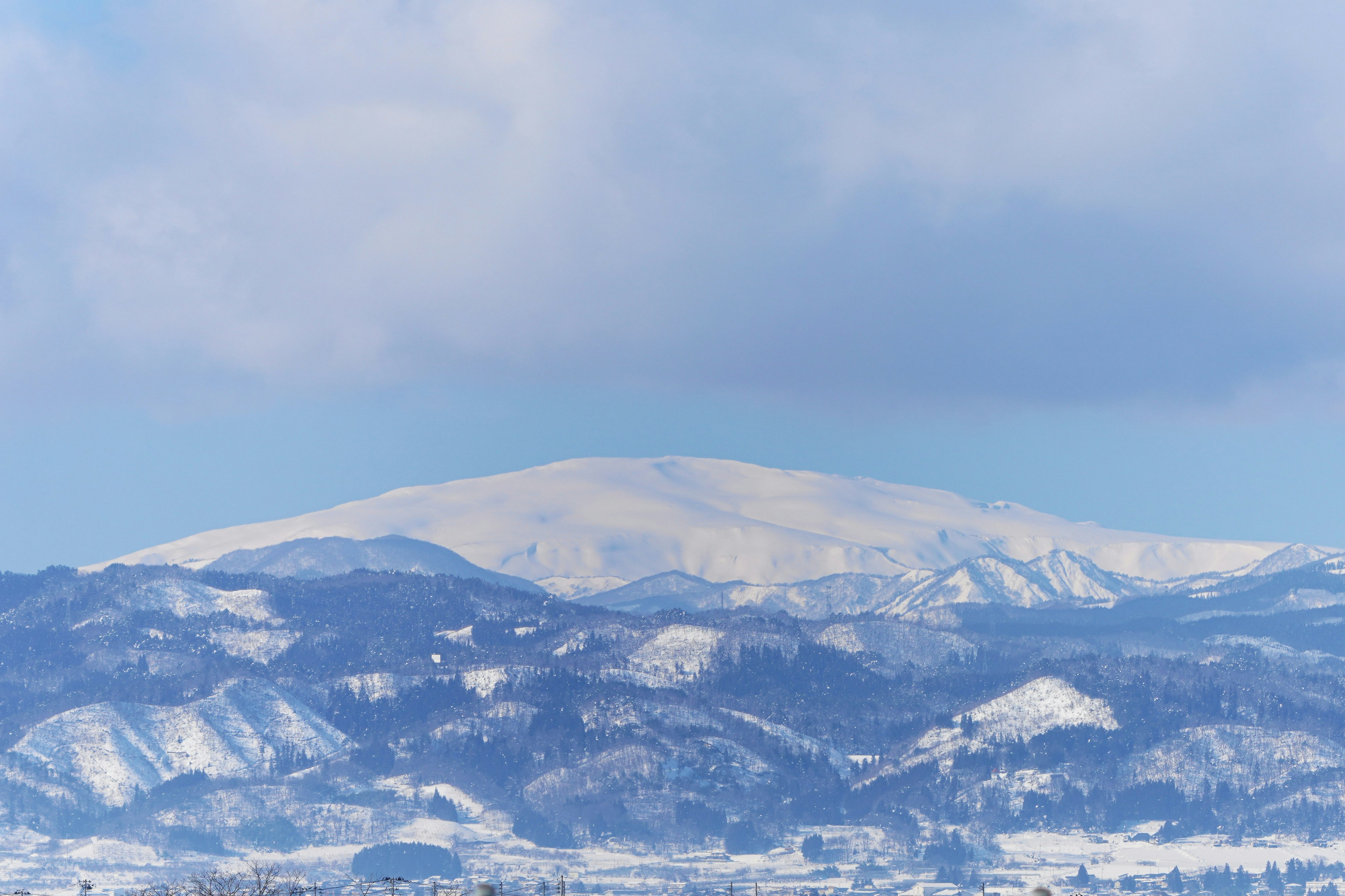 Paesaggio montano innevato con cielo blu e nuvole