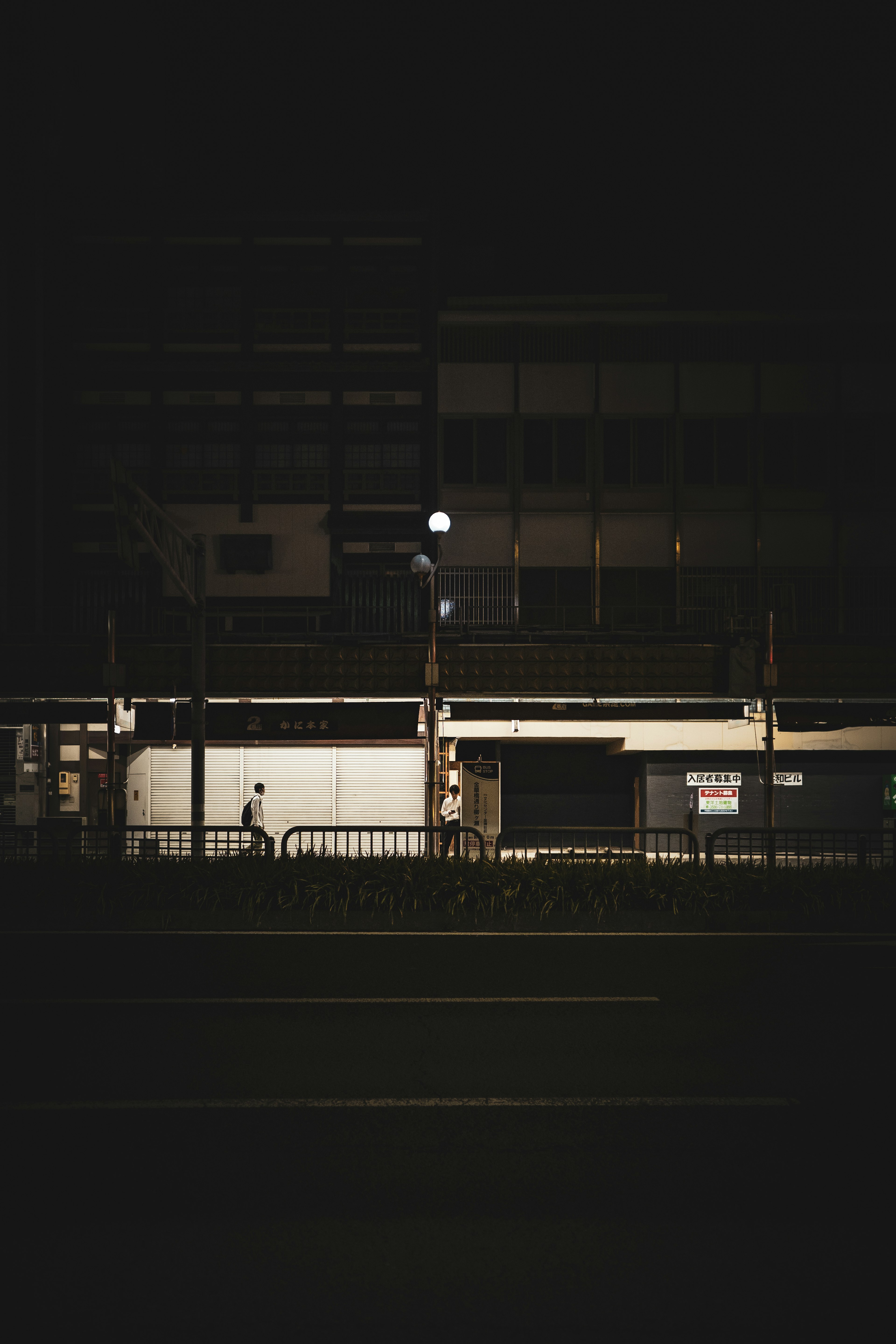 Dimly lit building in a night scene with a solitary figure