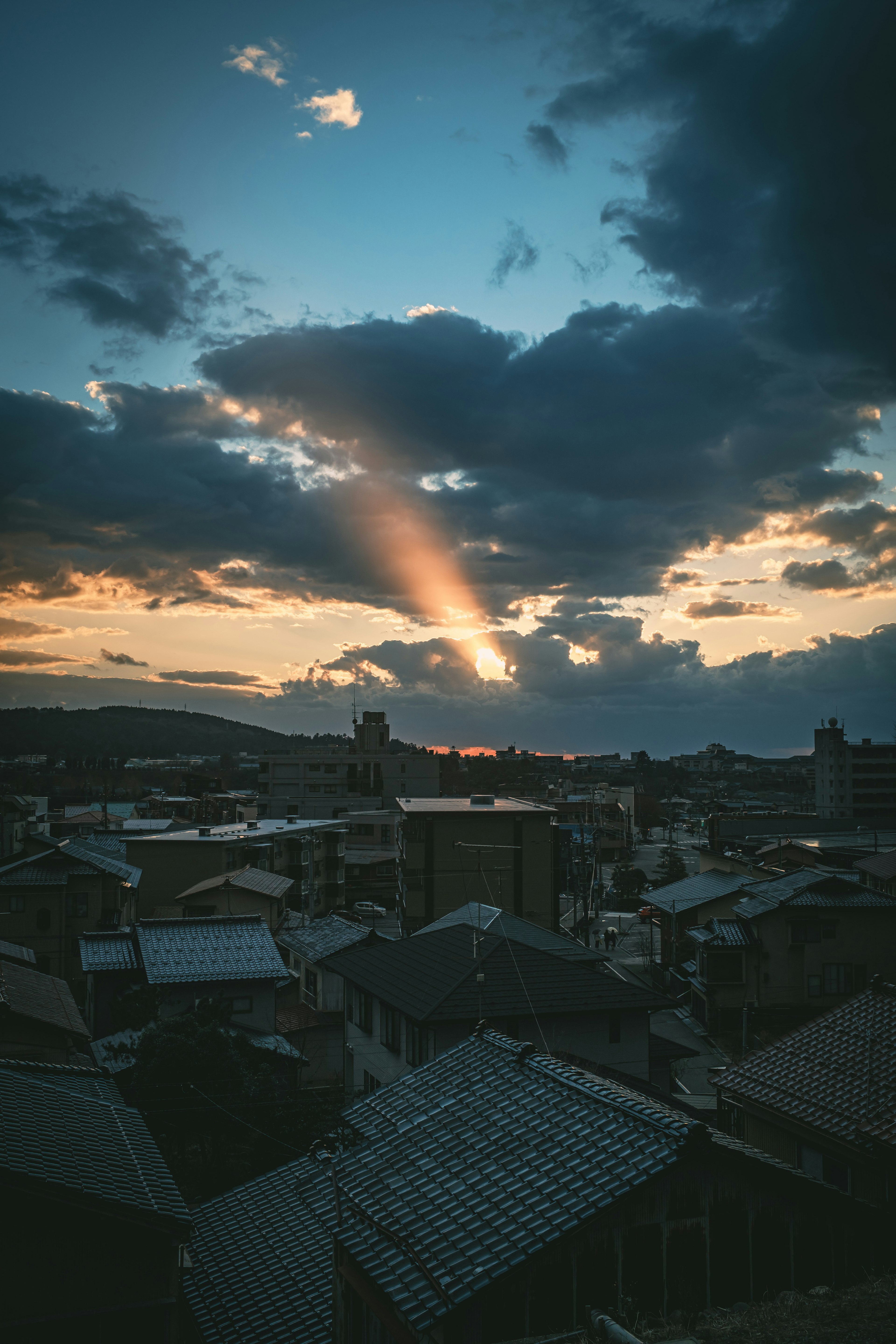 Paisaje urbano al atardecer con rayos de luz atravesando las nubes