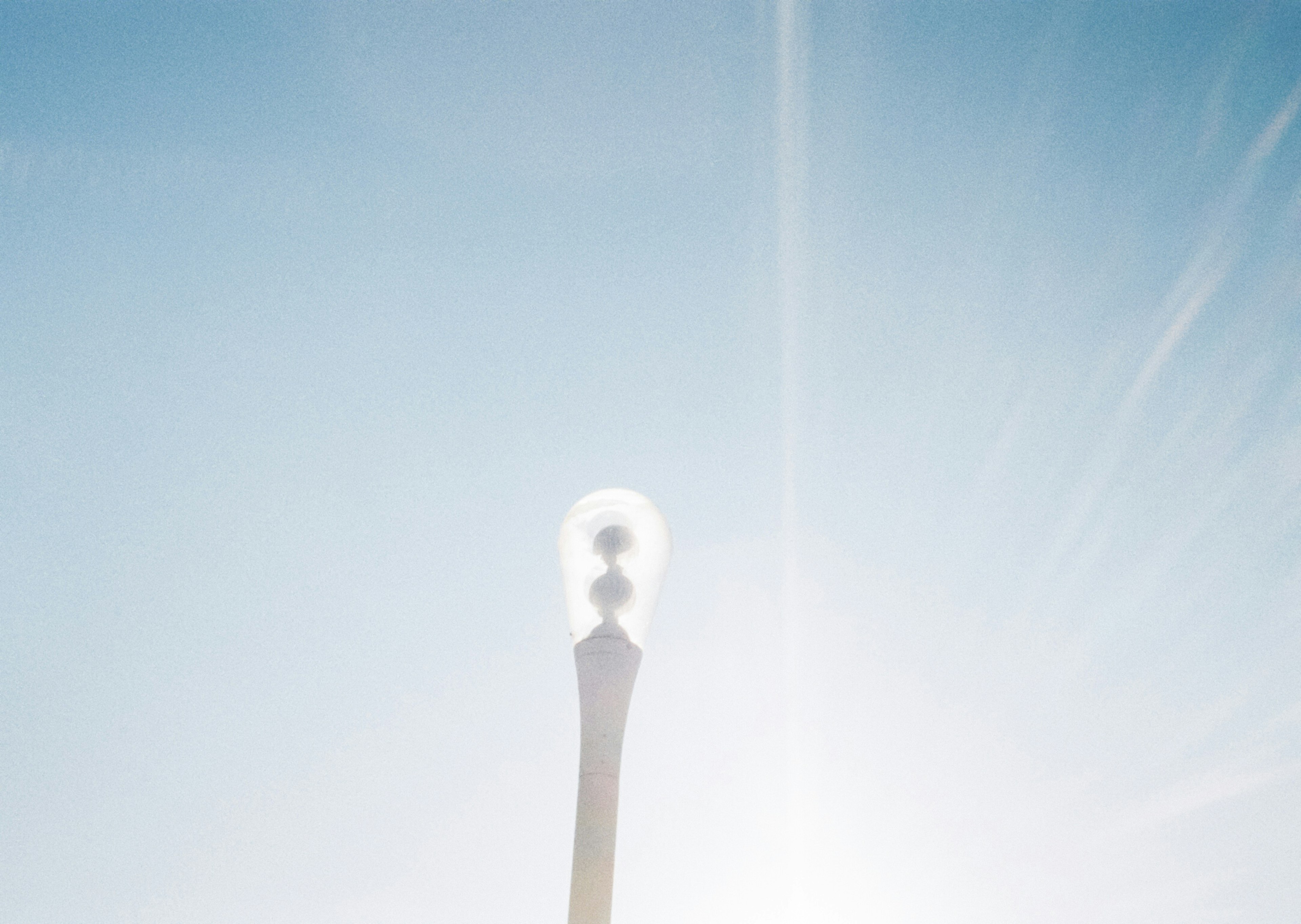 Silhouette of a unique streetlight against a blue sky