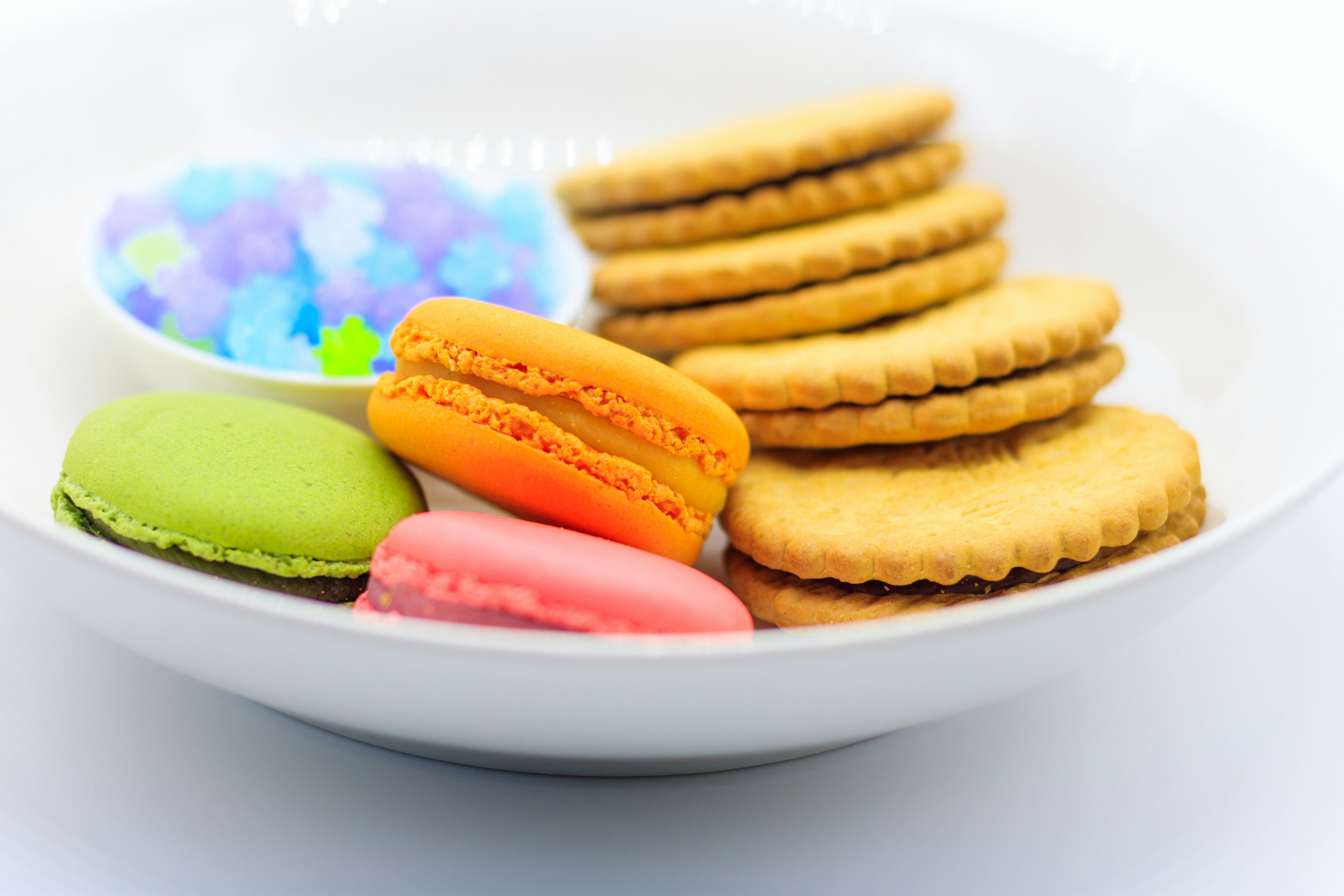 Macarons colorés et biscuits disposés sur une assiette blanche