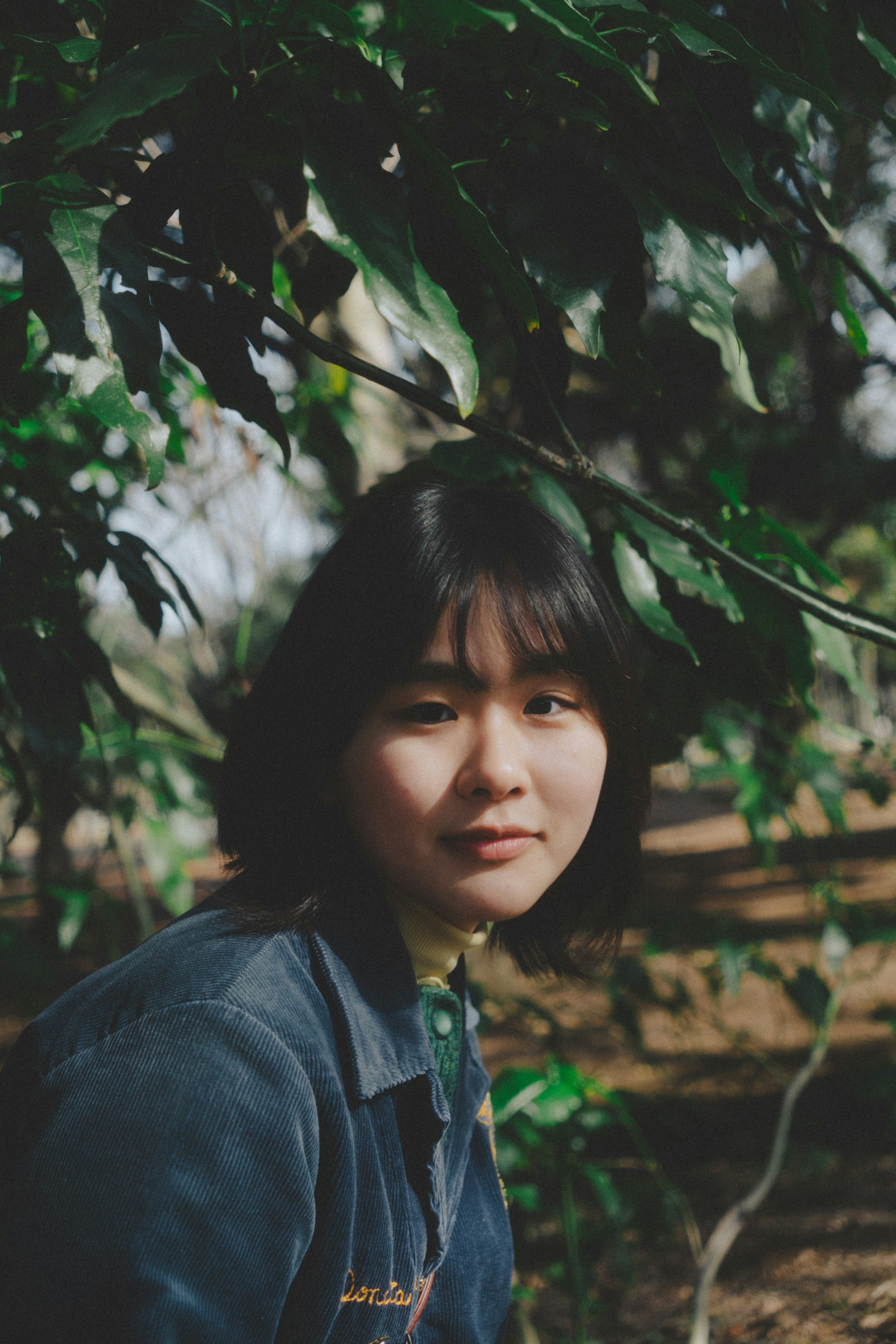 Portrait d'une femme parmi des feuilles vertes expression sereine dans la nature