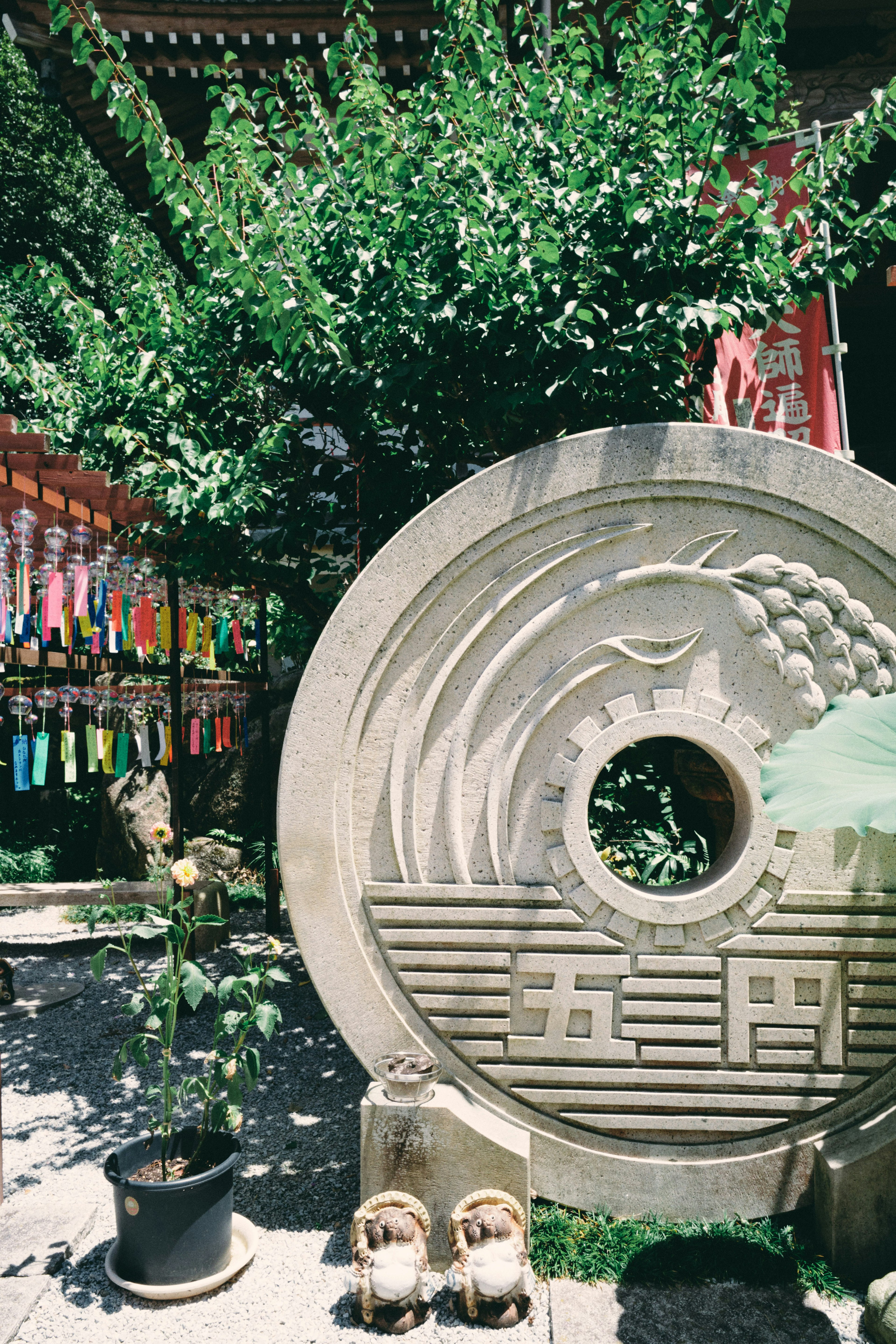 Sculpture circulaire en pierre avec des sculptures complexes entourée de verdure