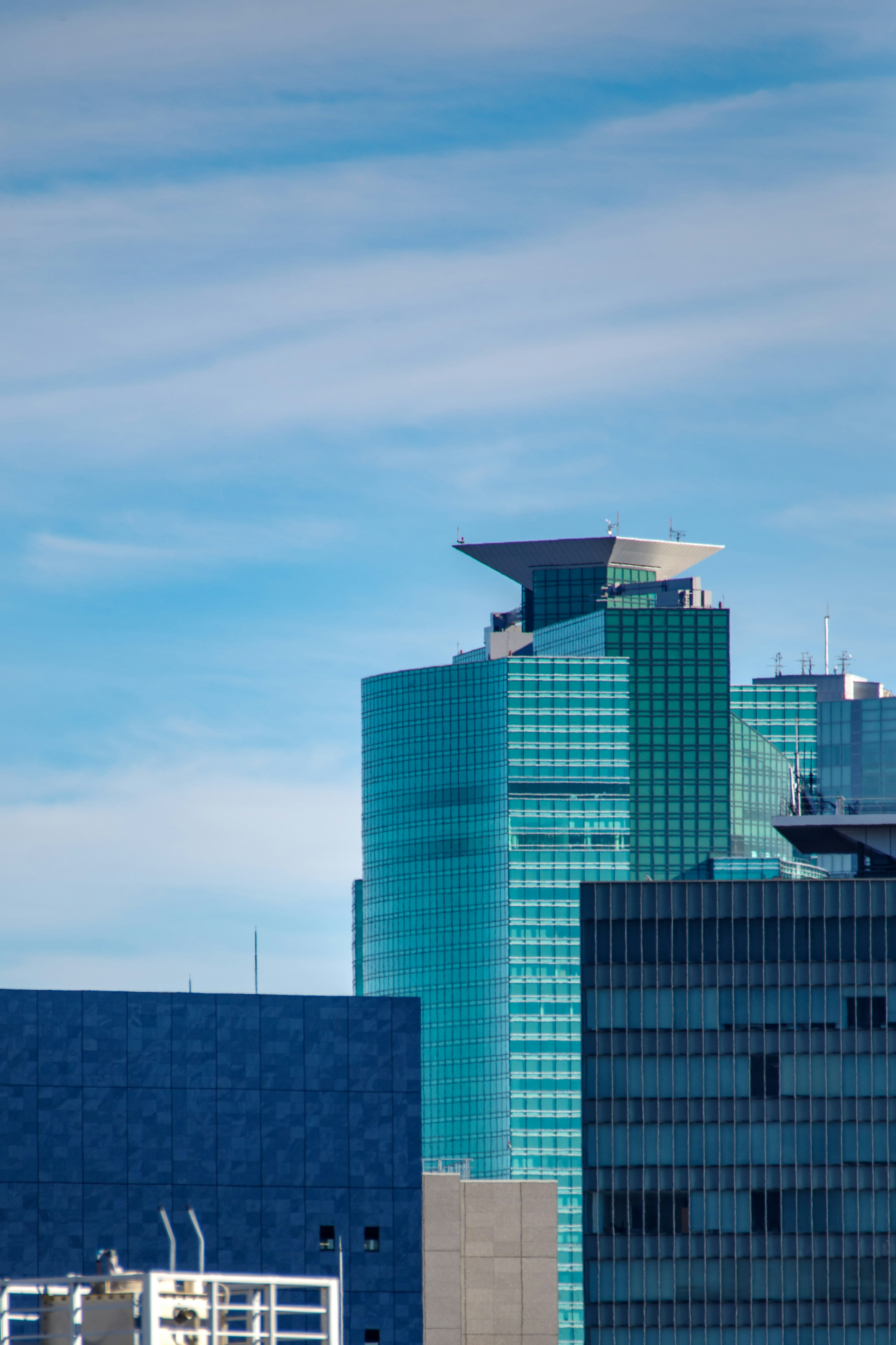 Gedung pencakar langit modern dengan fasad kaca di bawah langit biru