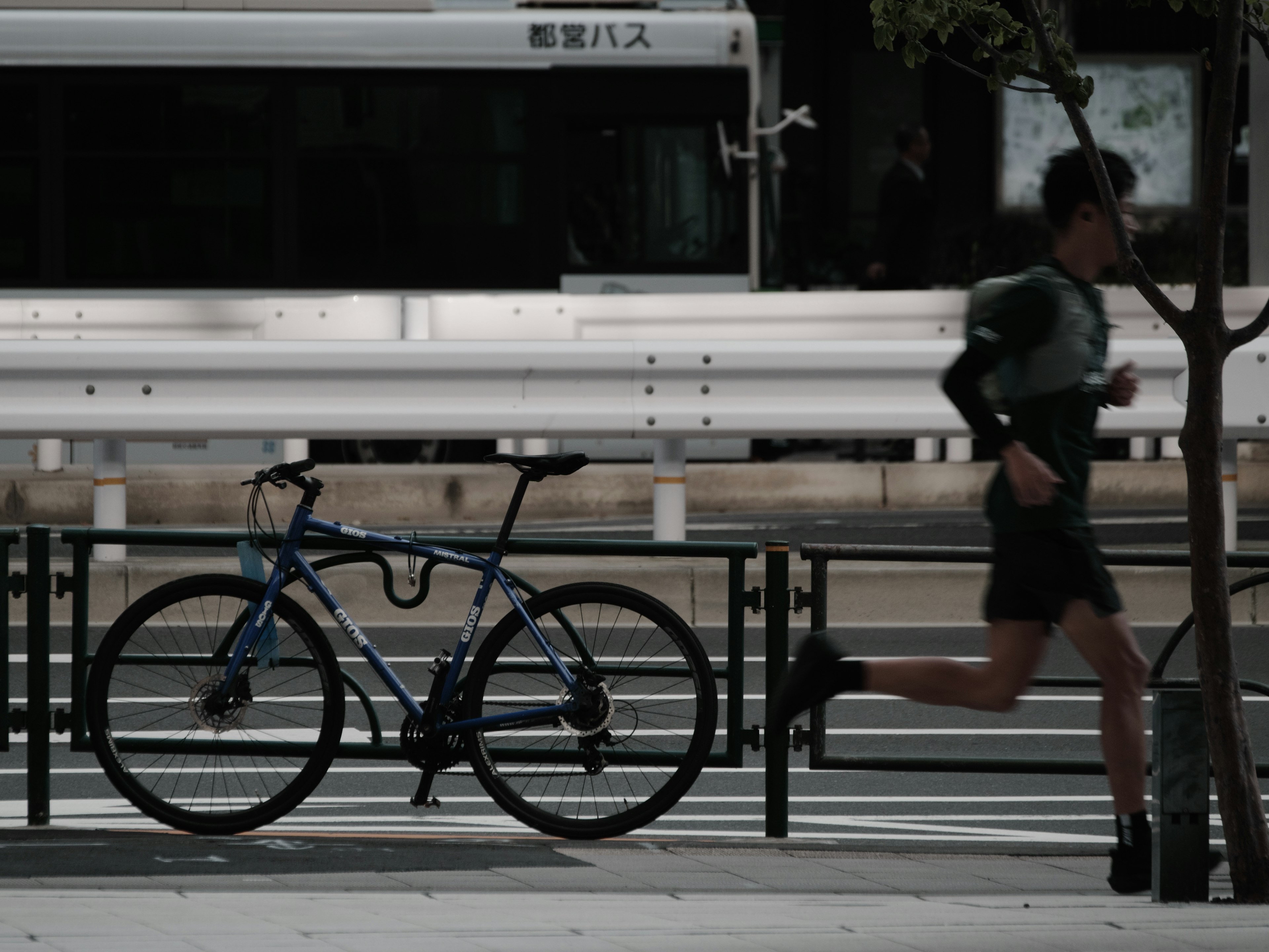 Un hombre corriendo en un parque junto a una bicicleta azul