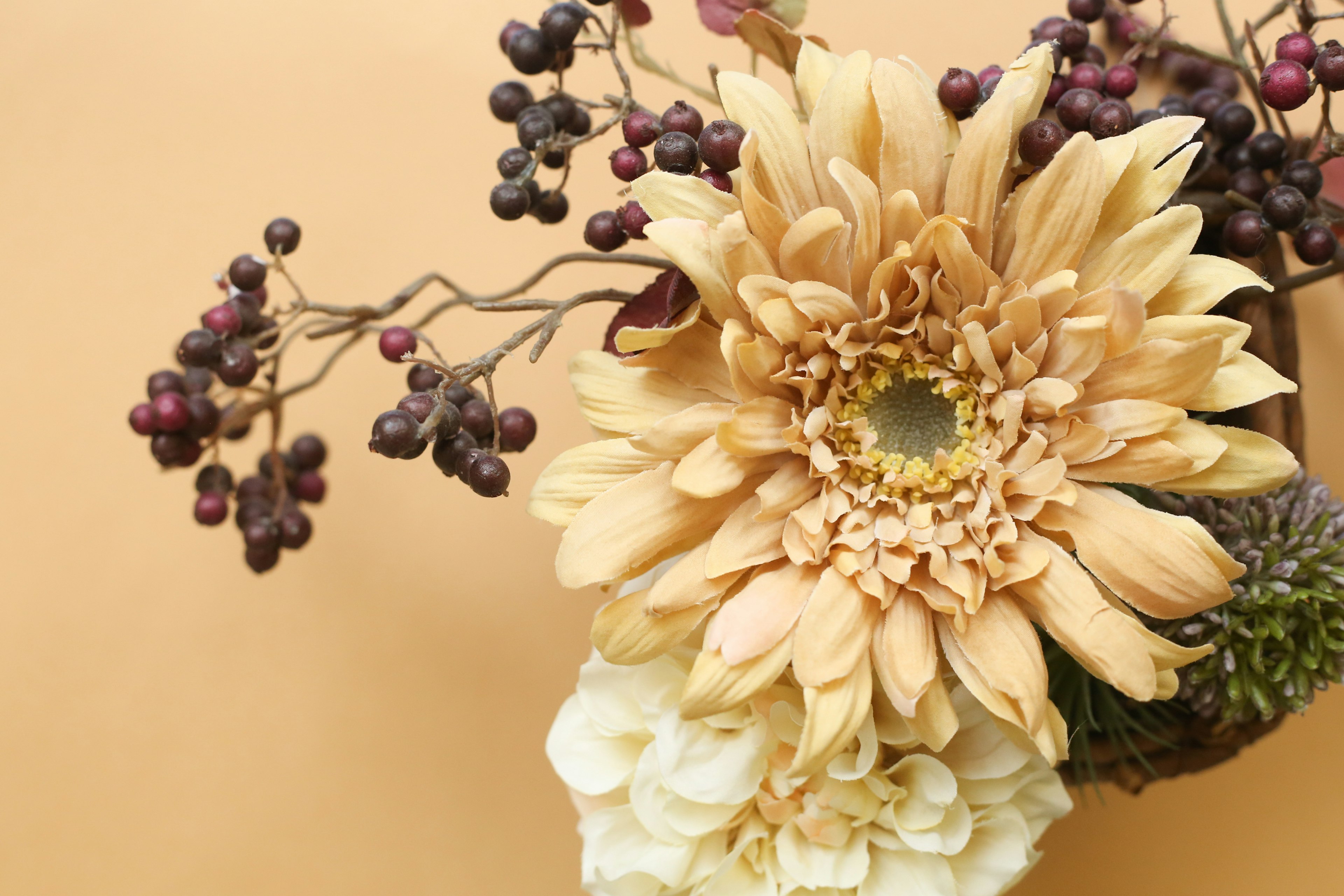 Floral arrangement featuring dried flowers and berries against a soft background