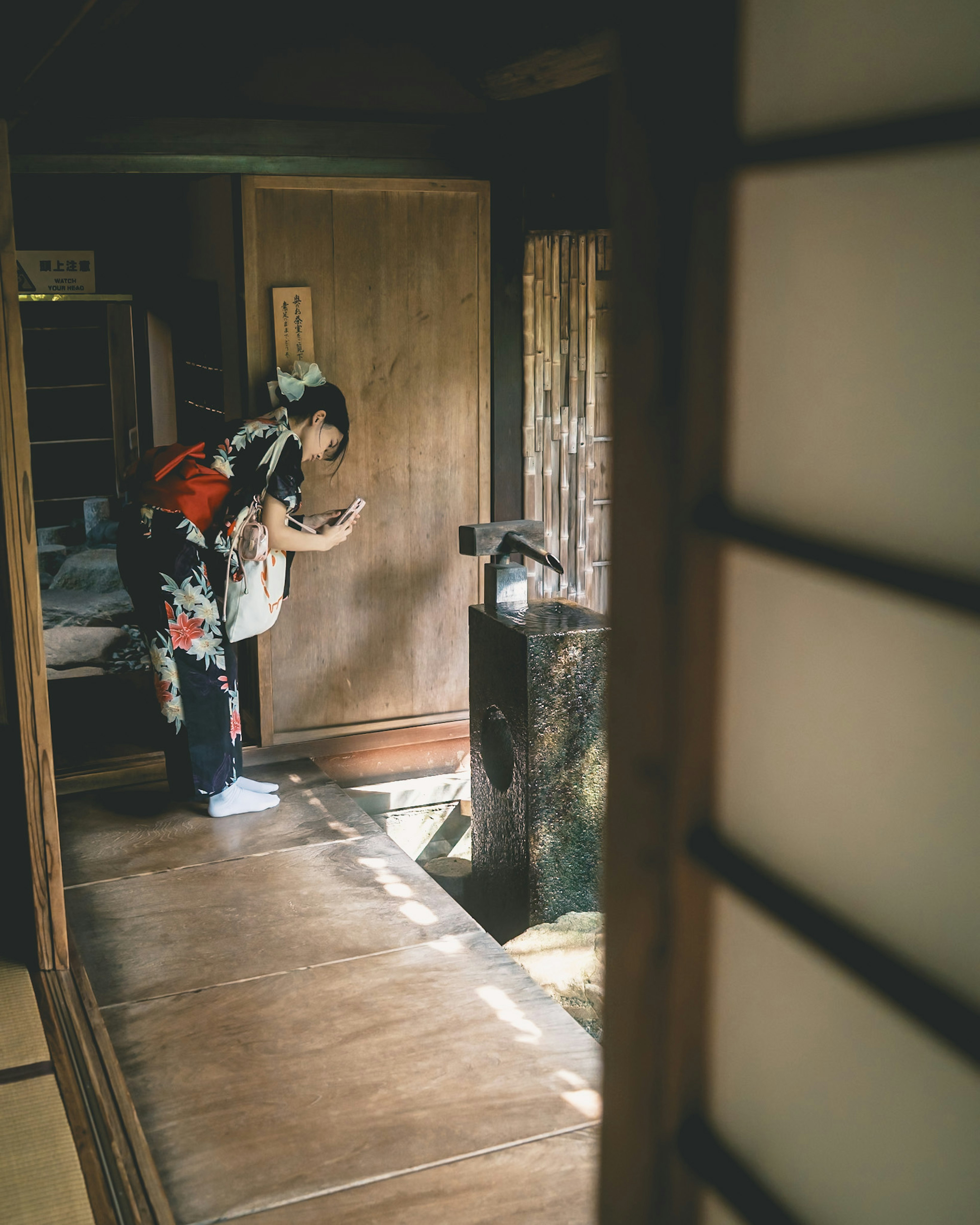 Seorang wanita berpakaian kimono berdiri di depan pintu dalam interior rumah tradisional Jepang