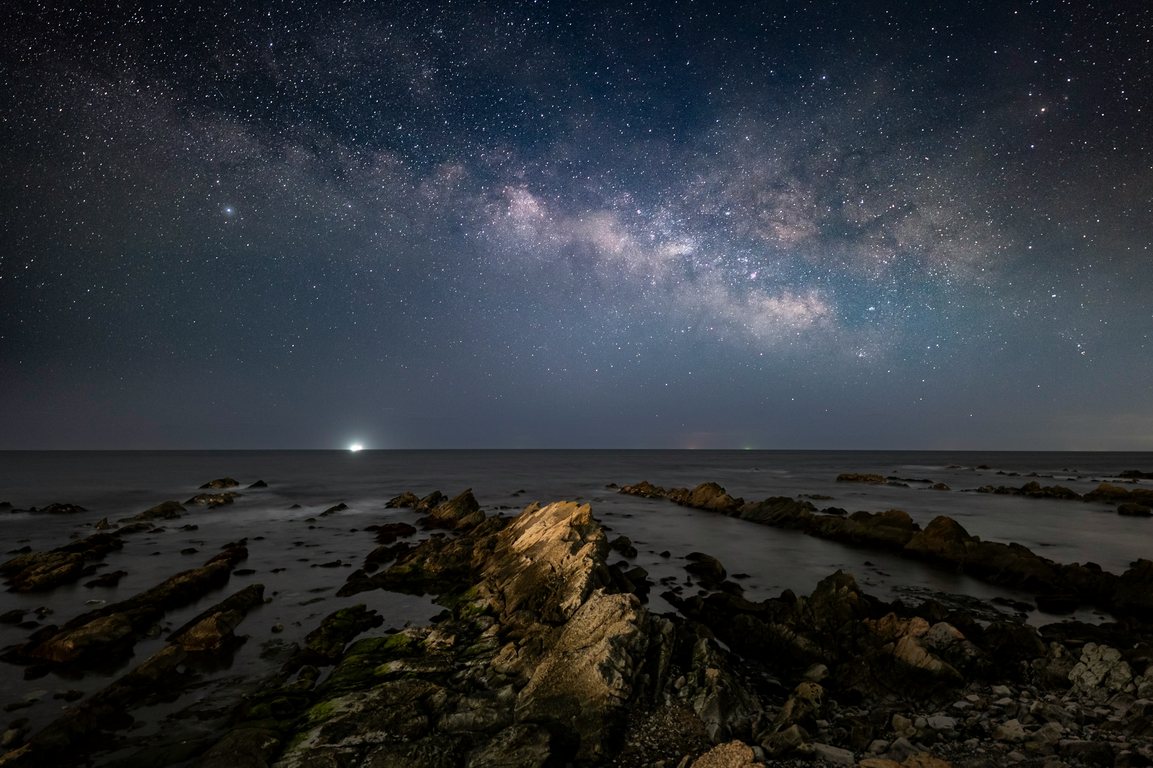 星空の下の海岸線と岩の風景に広がる天の川