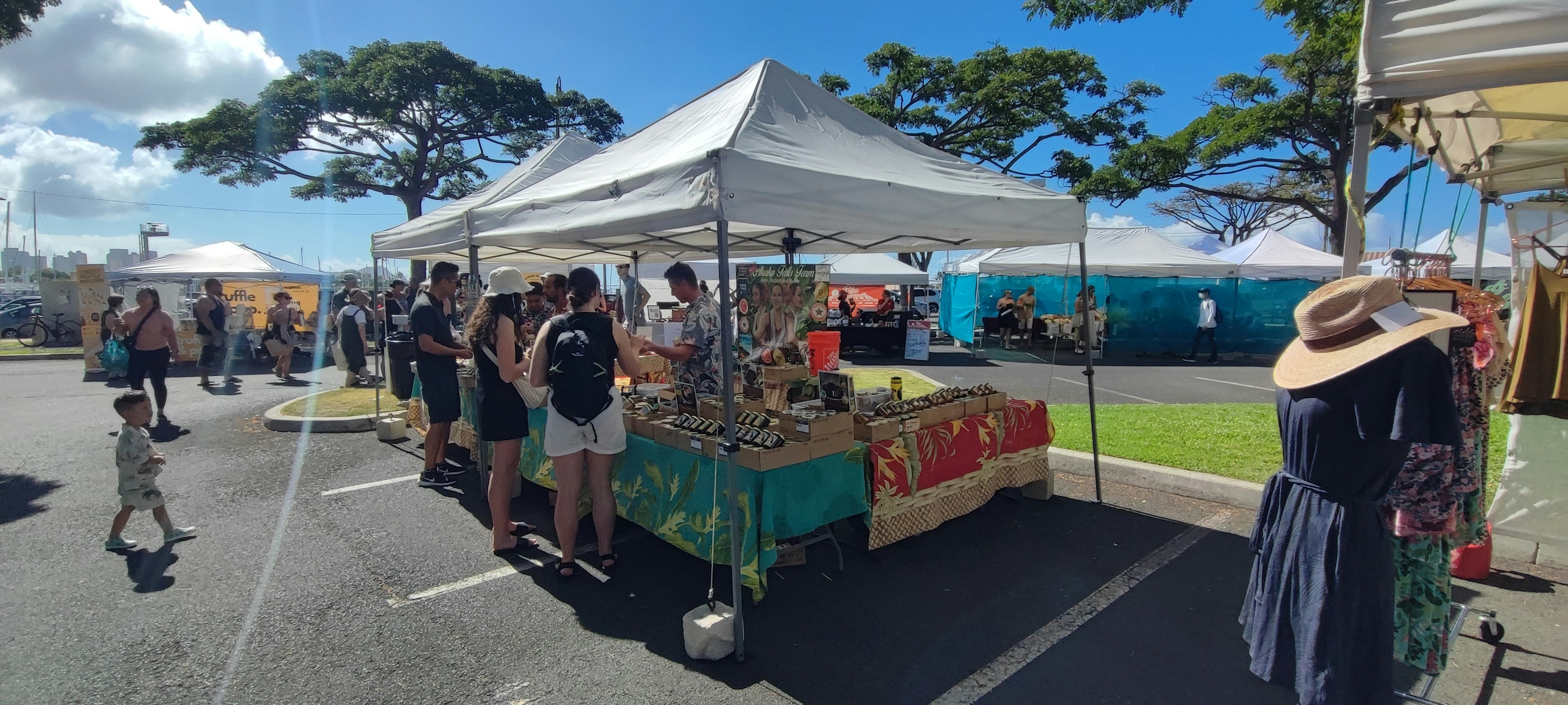 Puesto de mercado al aire libre con compradores y productos exhibidos