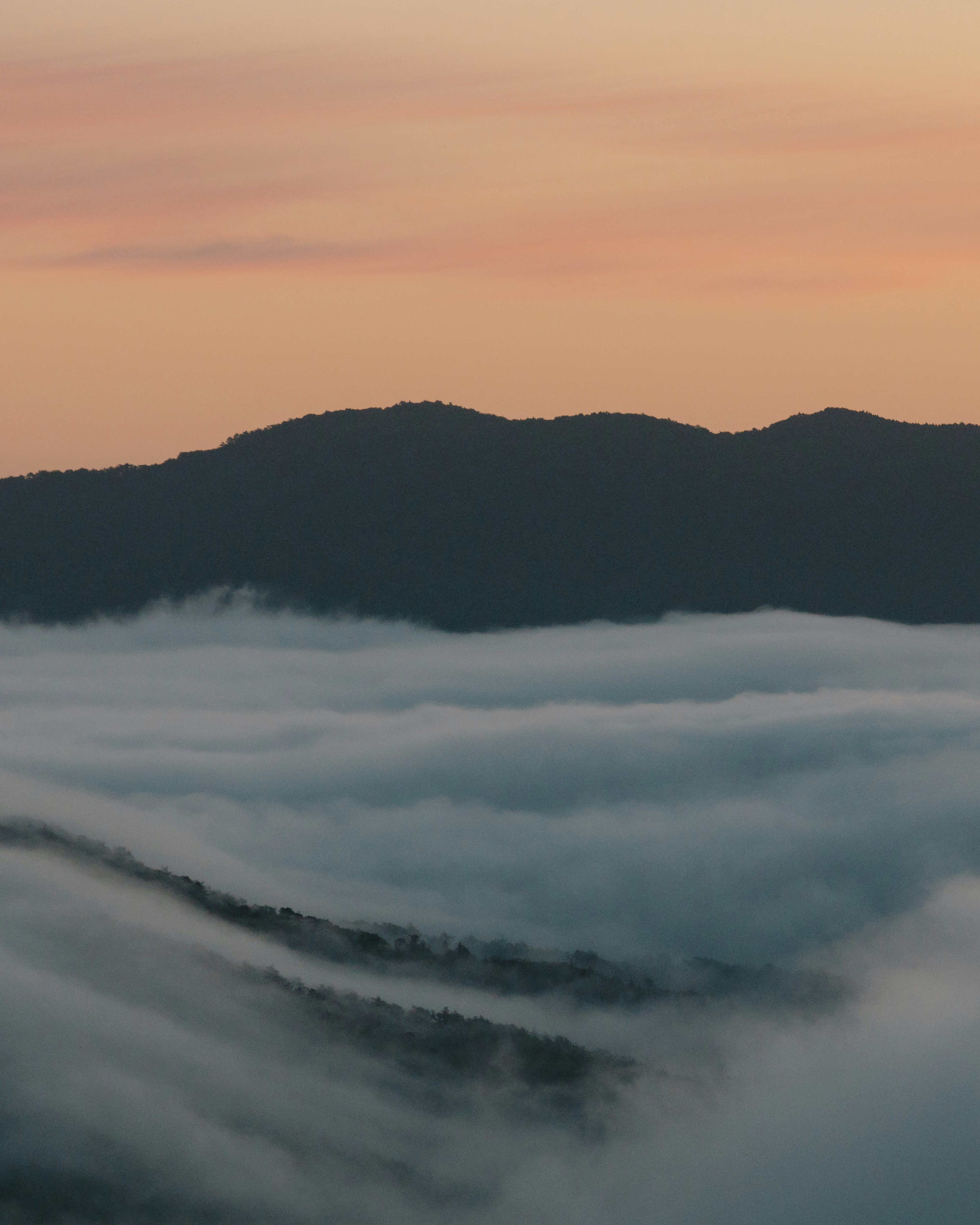 Silueta de montañas con un paisaje cubierto de niebla al atardecer