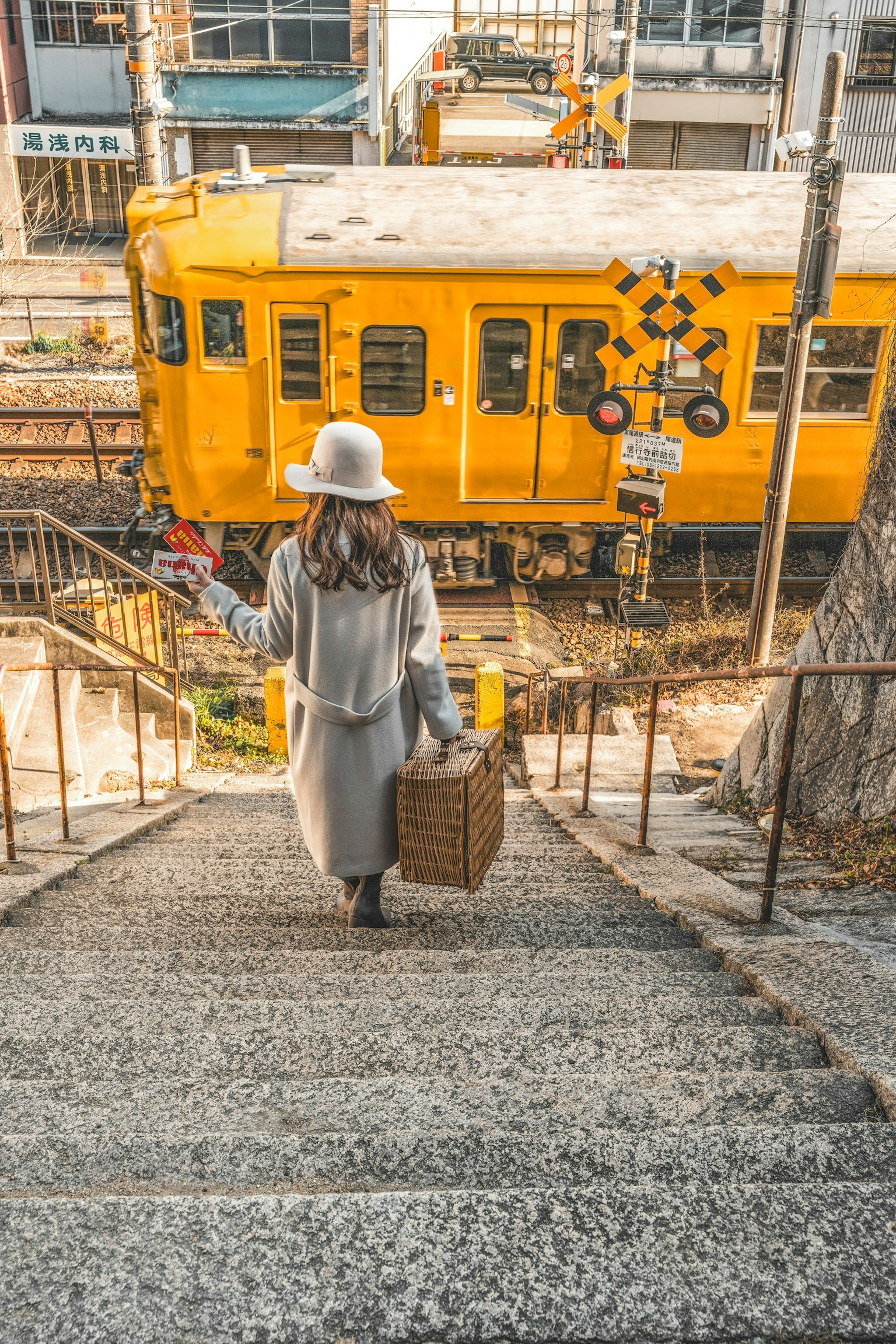 一位女性在黃色火車前走下樓梯