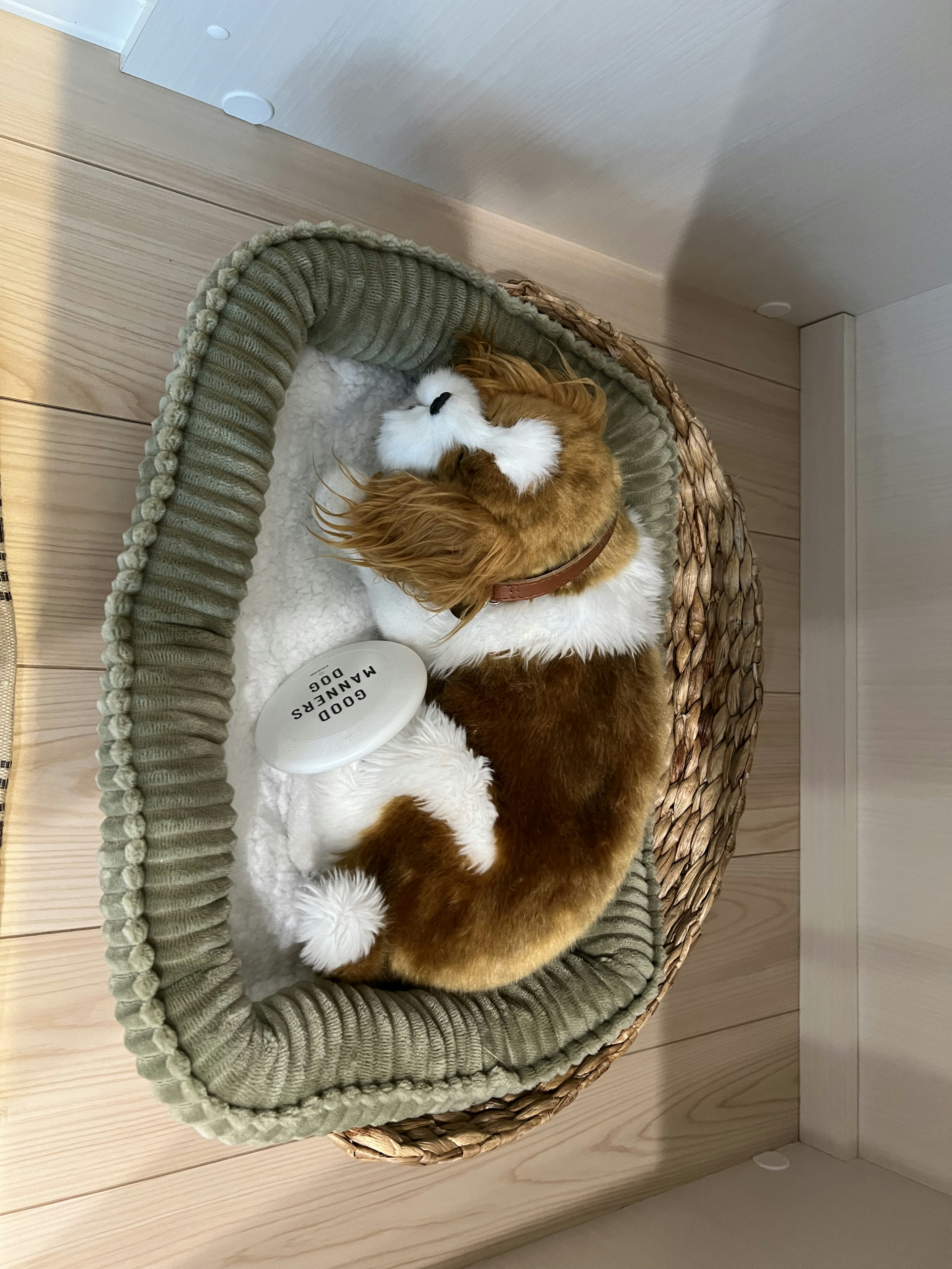 A brown and white stuffed dog lying in a small wicker basket