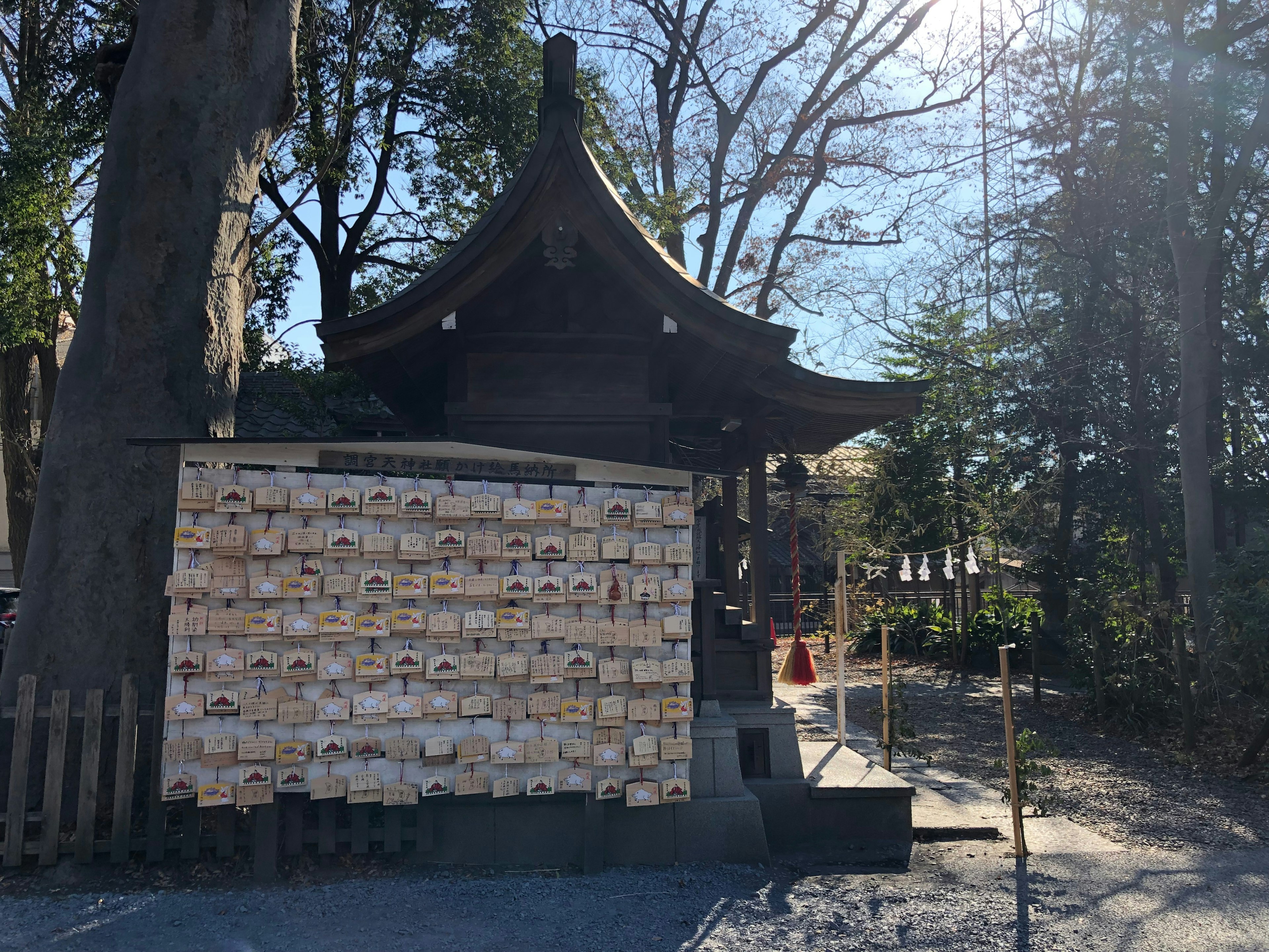 A shrine building with a wall displaying many votive tablets