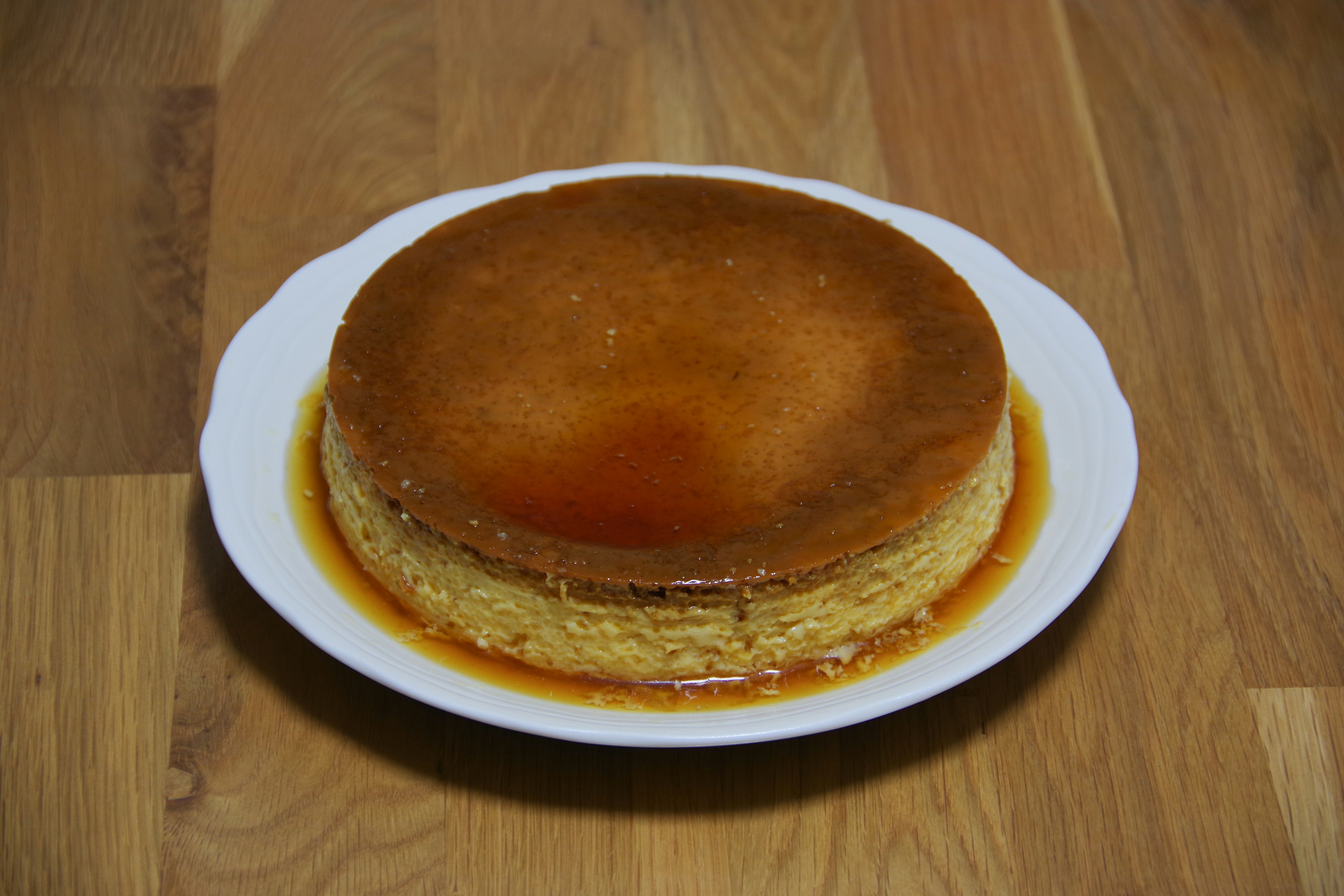 Flan de caramelo brillante en un plato blanco