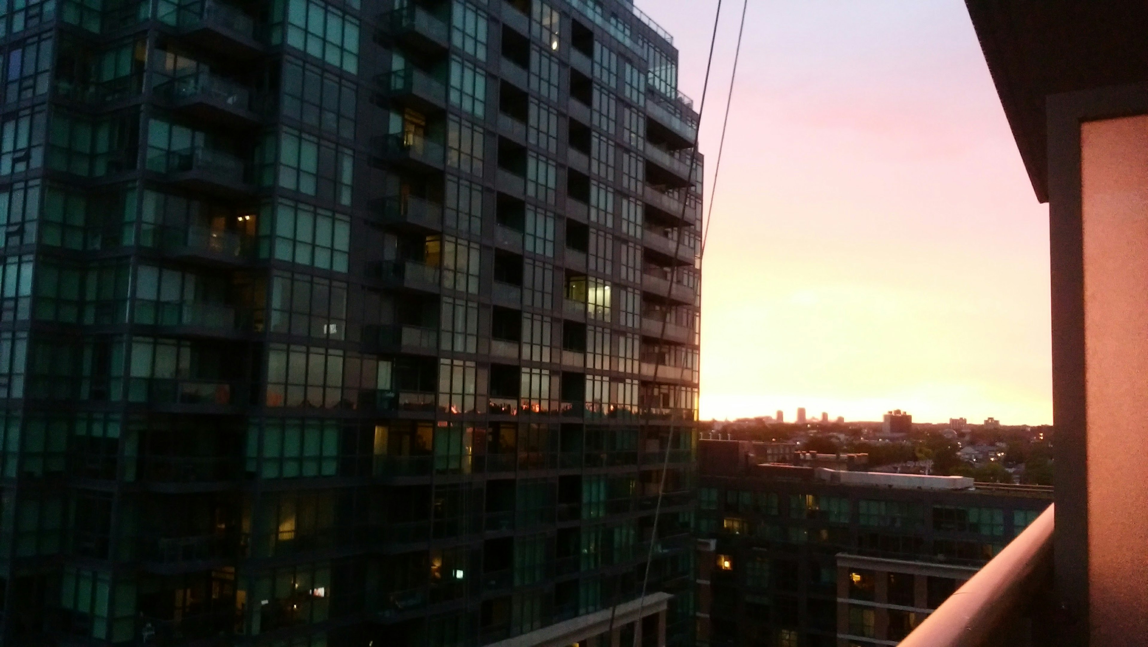 Vue du coucher de soleil depuis un balcon sur des immeubles modernes