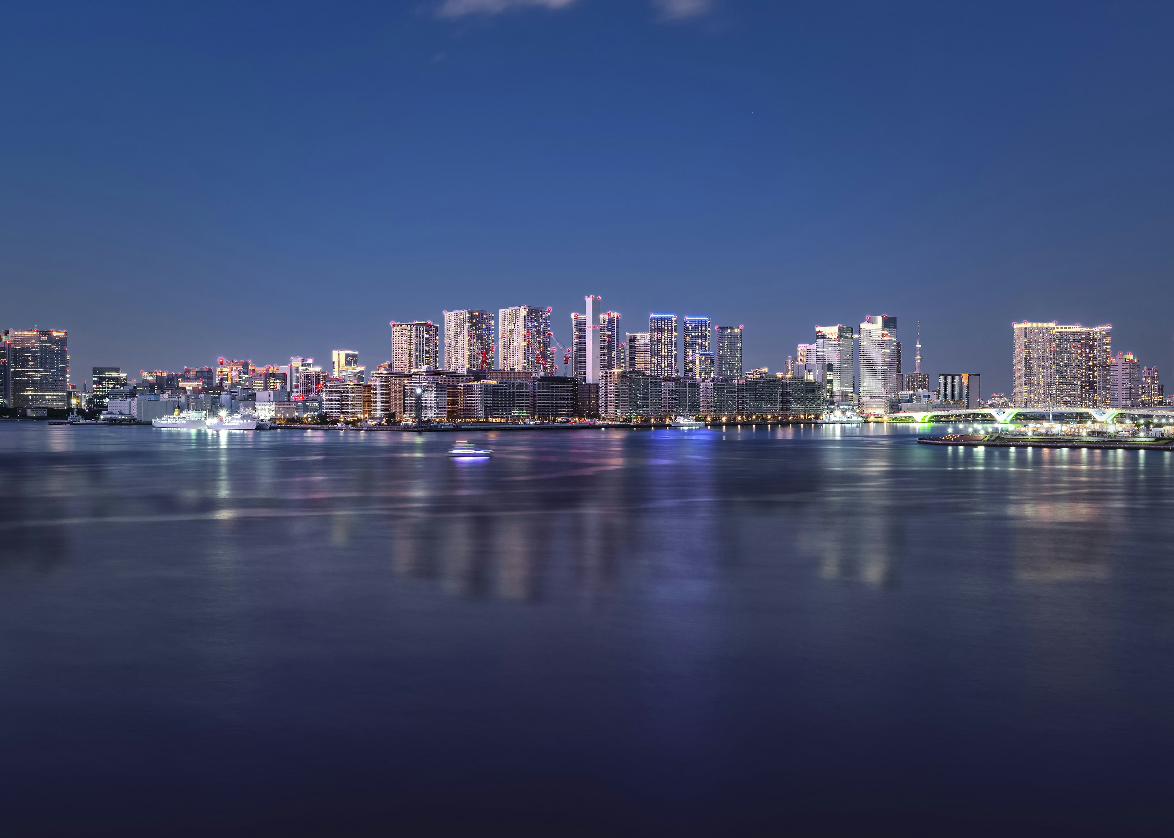 Silhouette de la ciudad reflejándose en el agua por la noche con luces coloridas