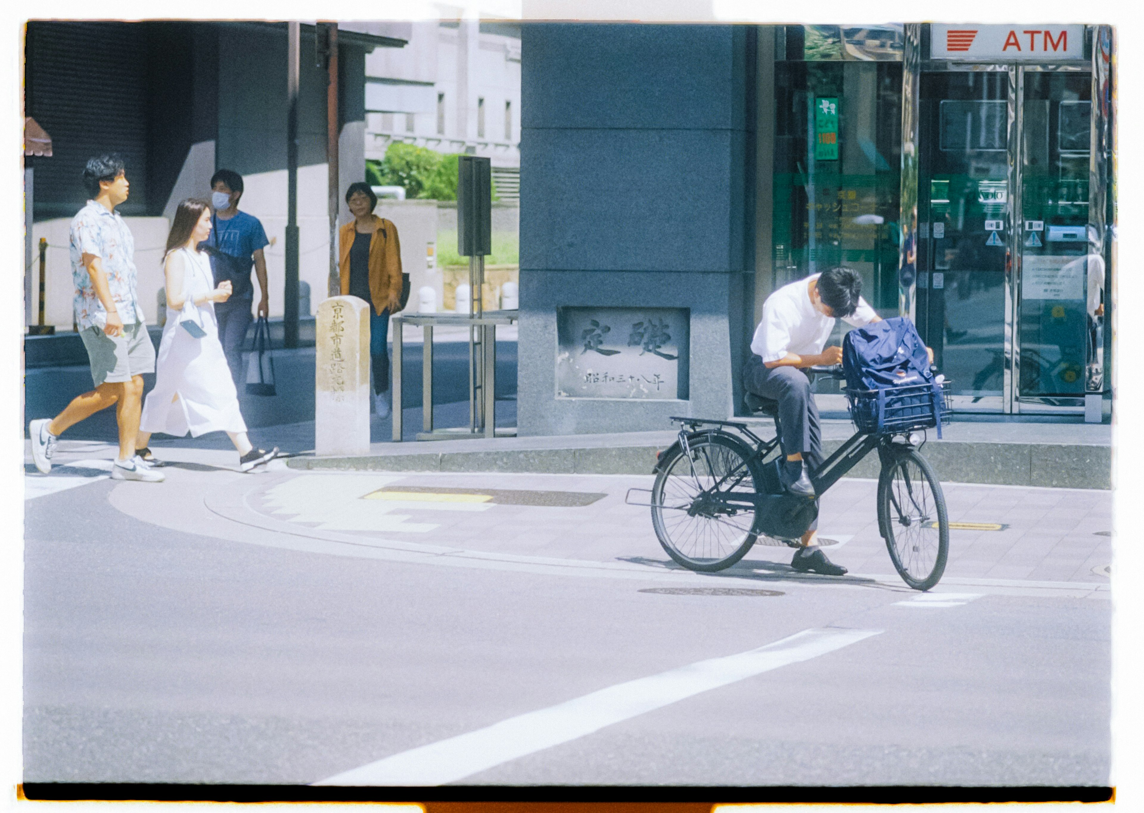 街角場景，有騎自行車的男士和行人