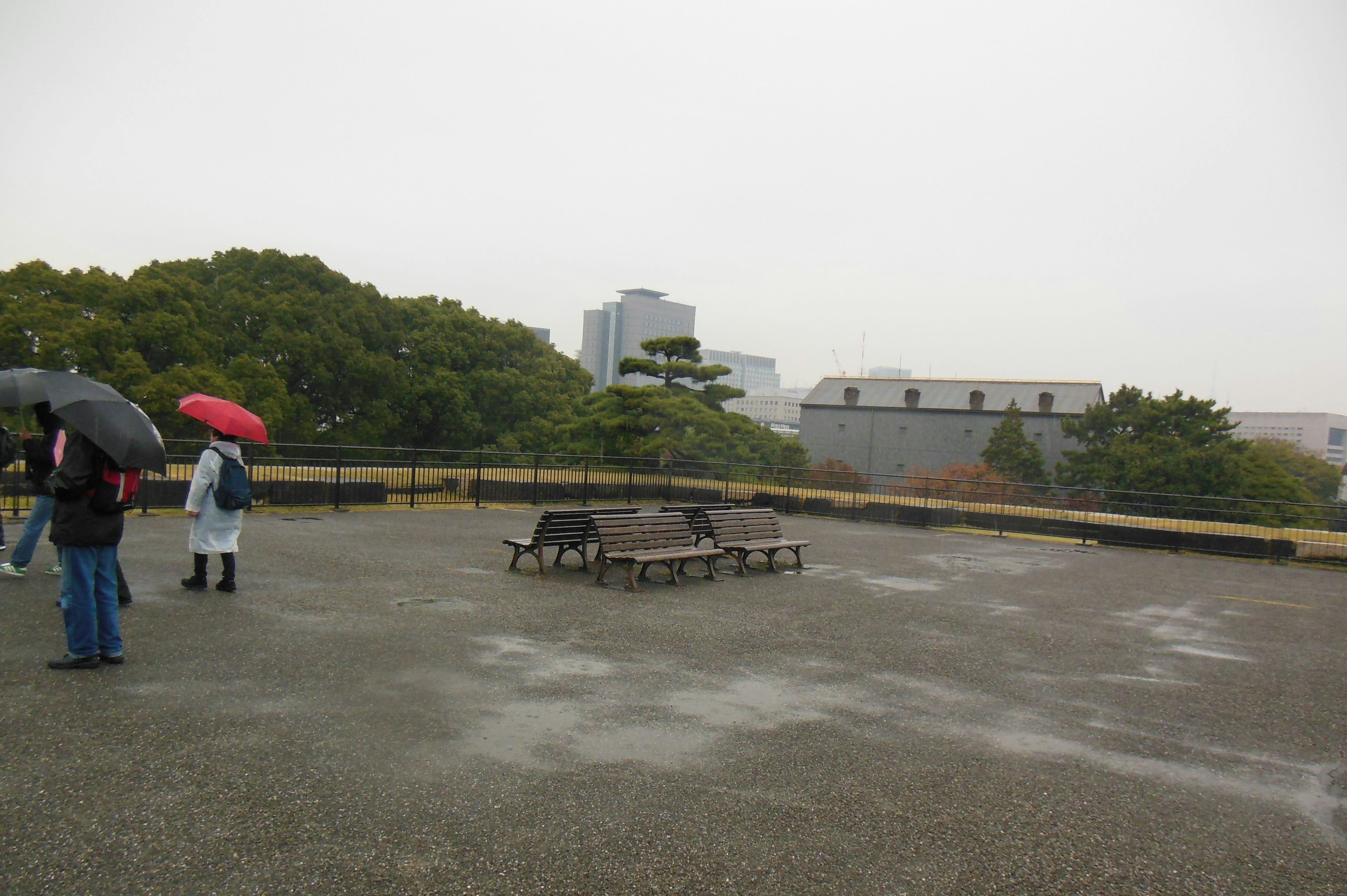 雨の中で傘を持った人々が立っている広場の風景