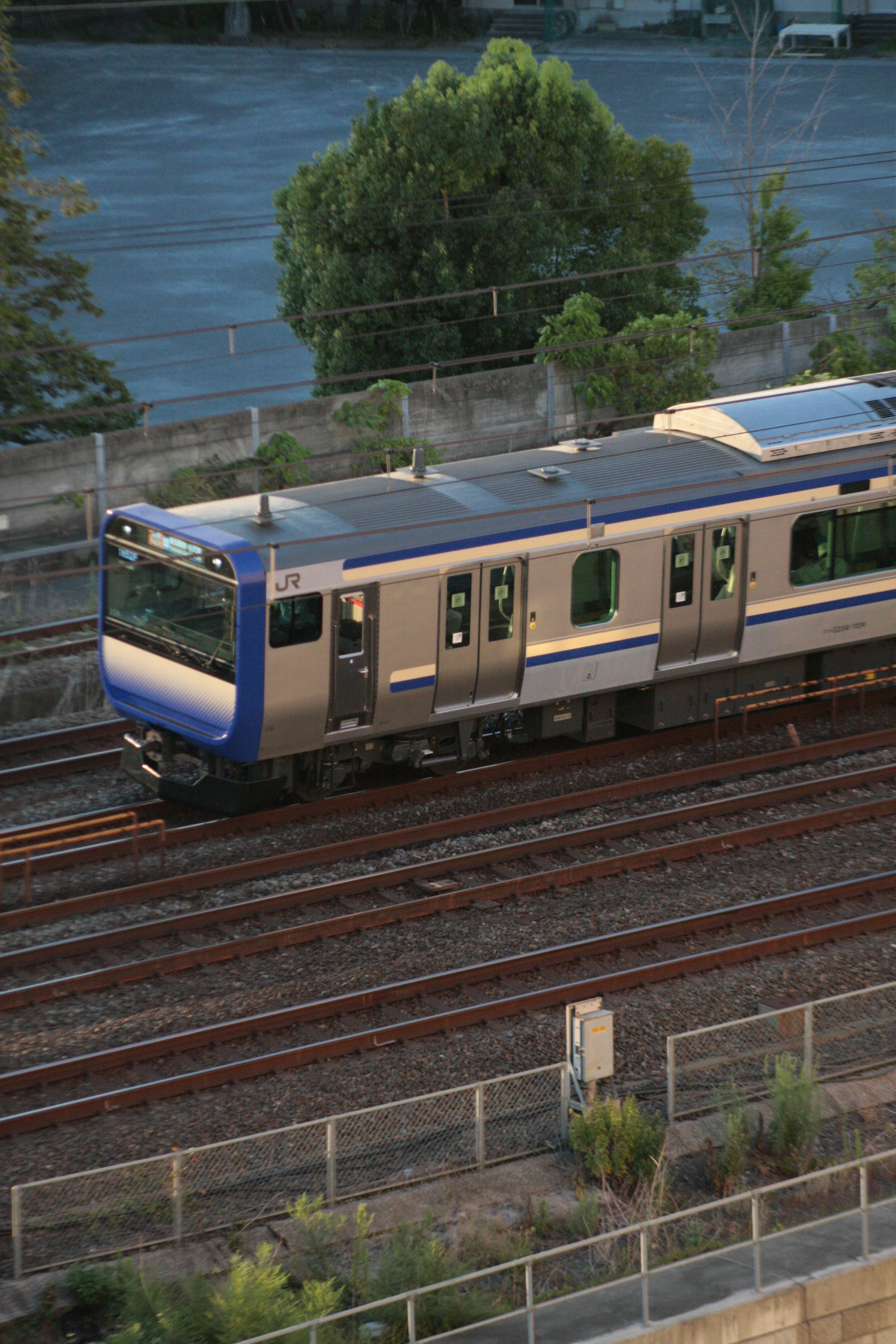 Silver train with blue accents traveling on railway tracks