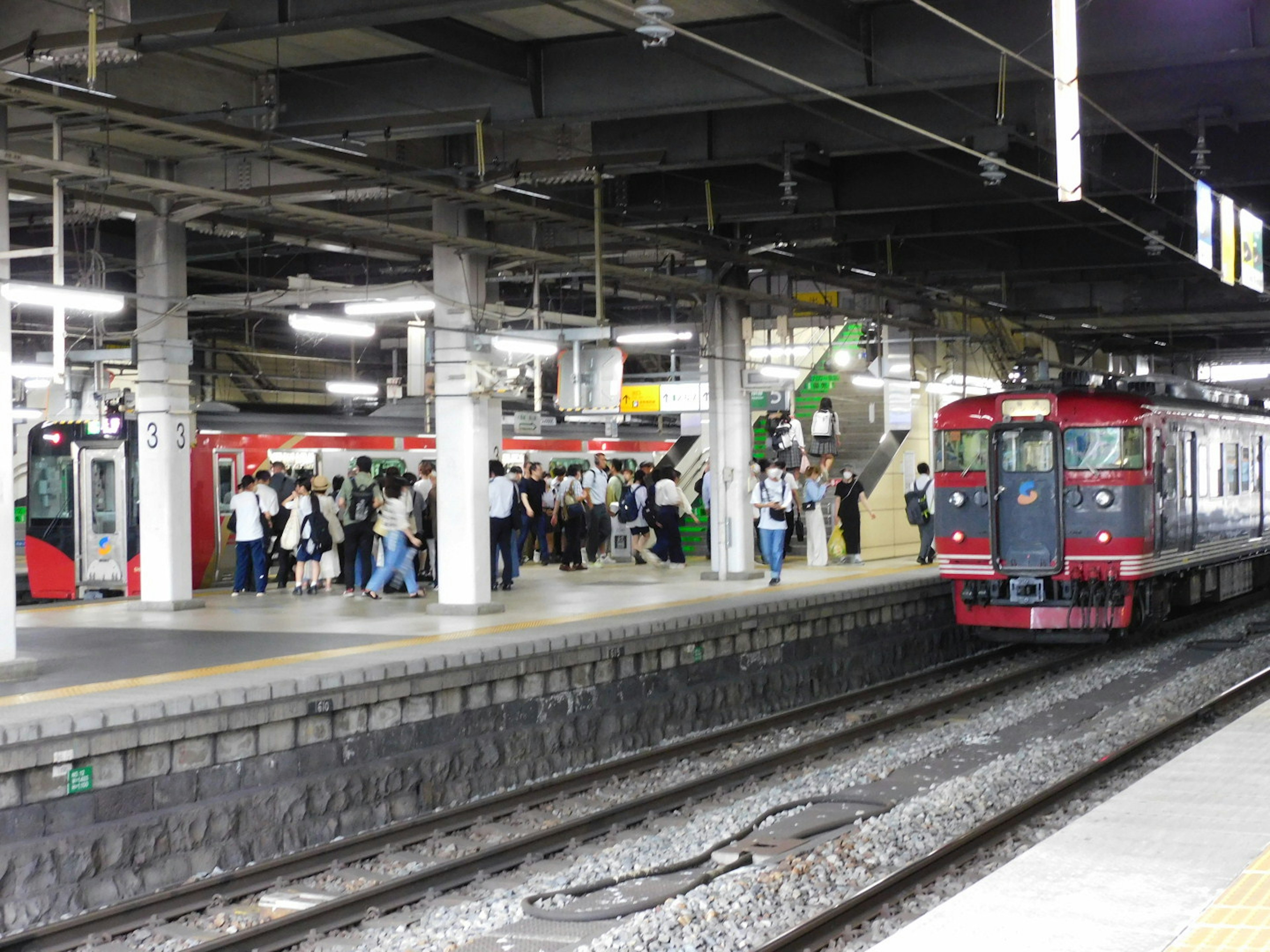 Tren rojo en la estación con pasajeros esperando