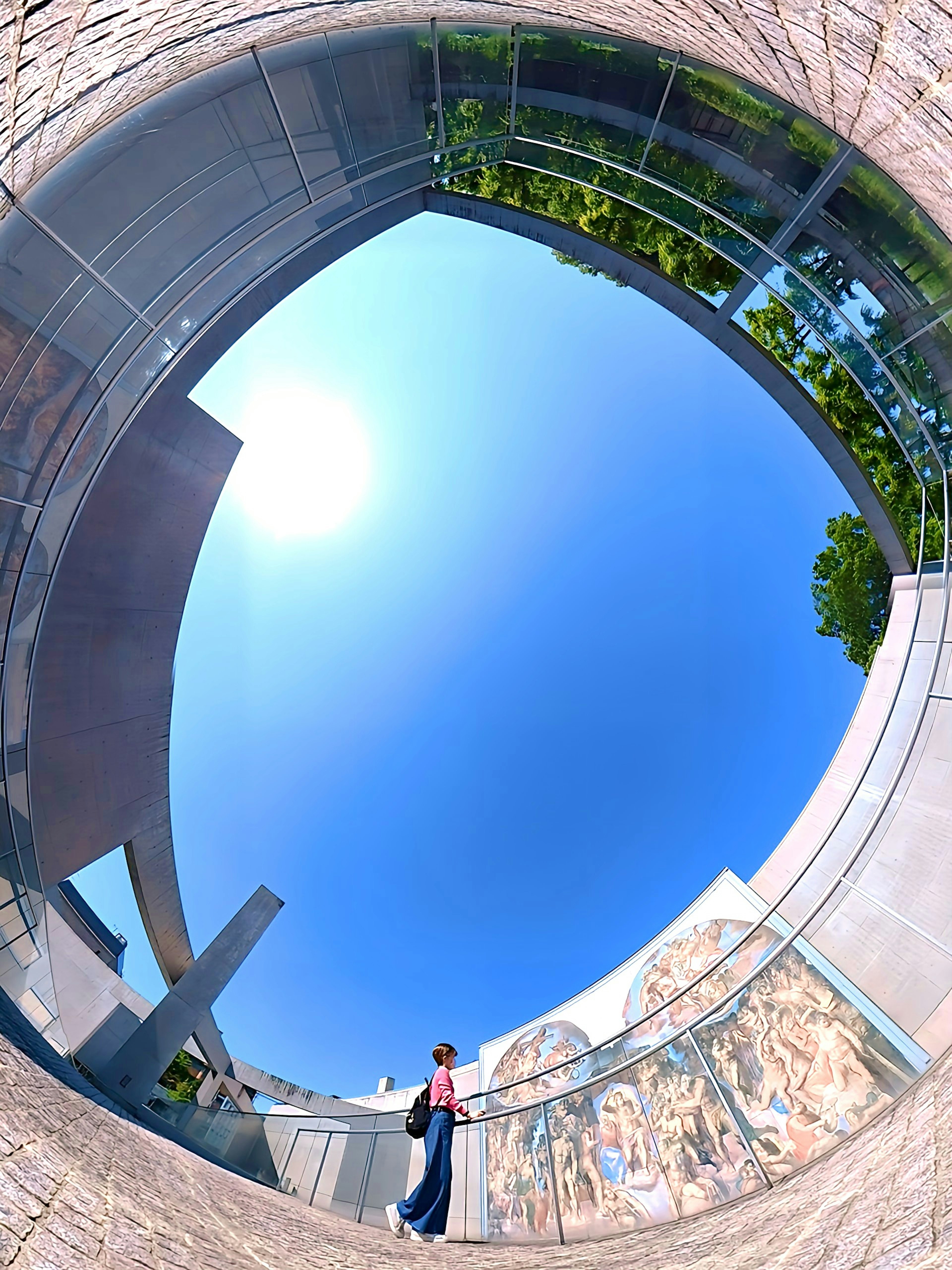 A person walking under a blue sky with a modern circular architectural design