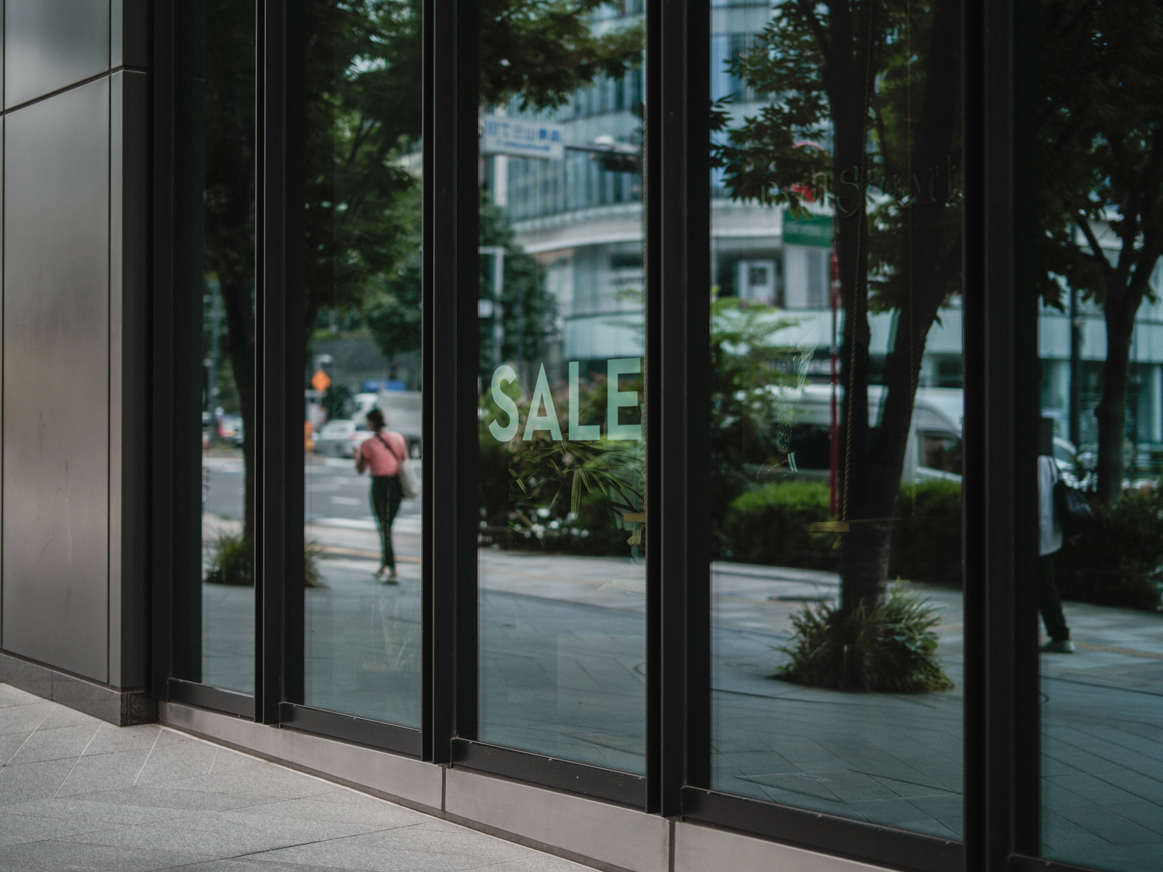 Reflected cityscape in glass windows with the word SALE