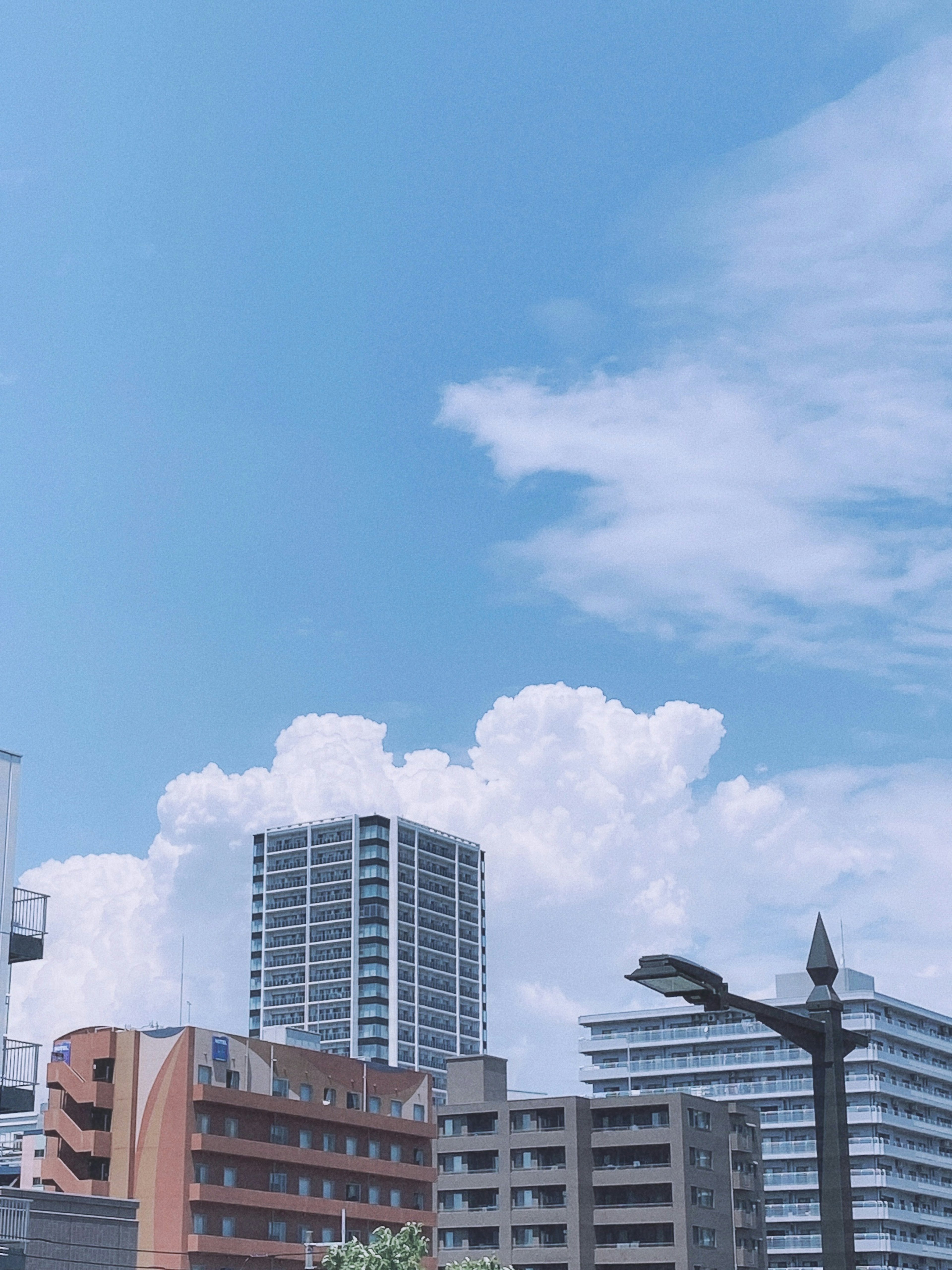 青空と白い雲が広がる都市の風景 高層ビルと低層ビルが並ぶ風景