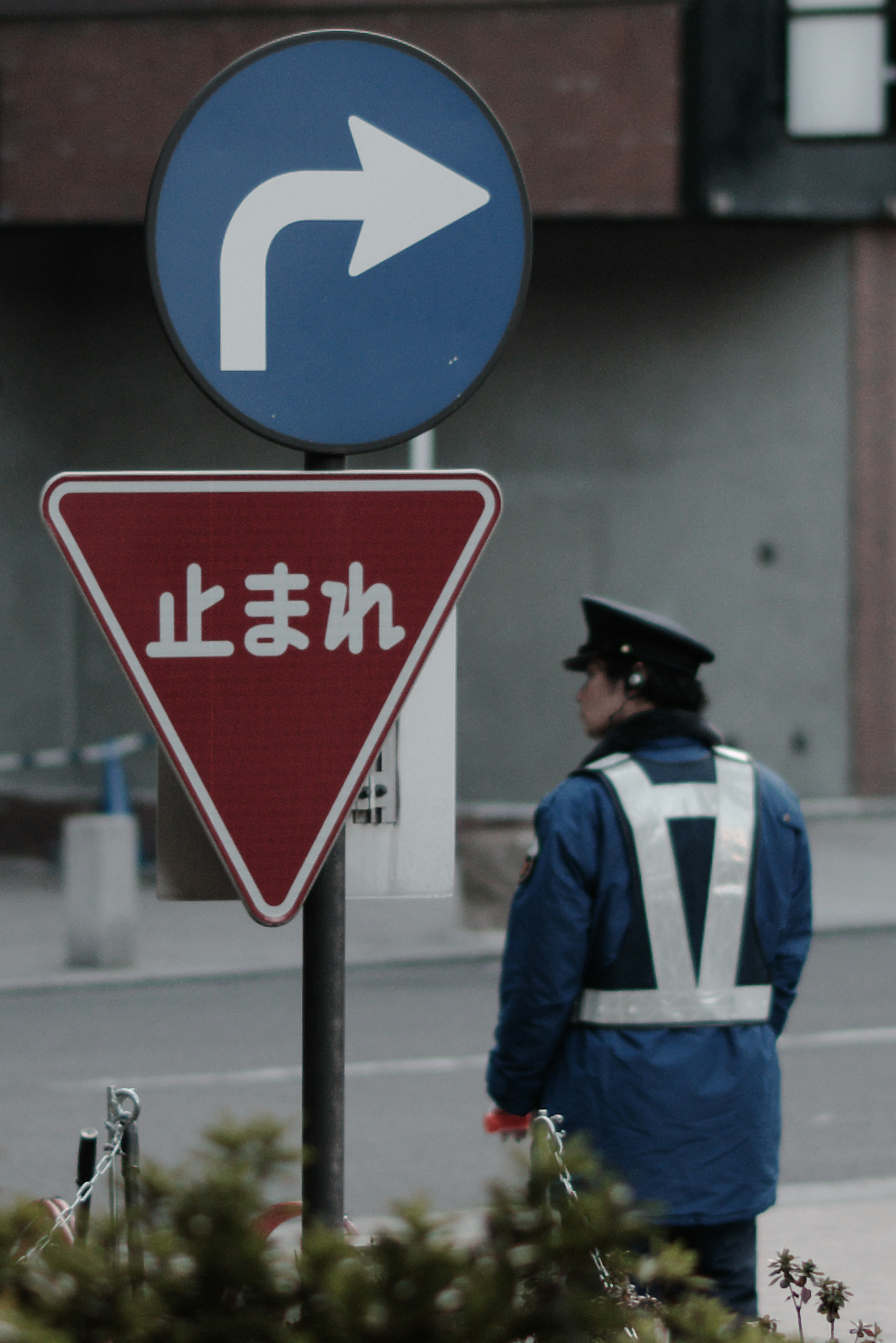 Polizist steht vor einem blauen Rechtsabbiegeschild und einem roten Vorfahrt gewähren Schild