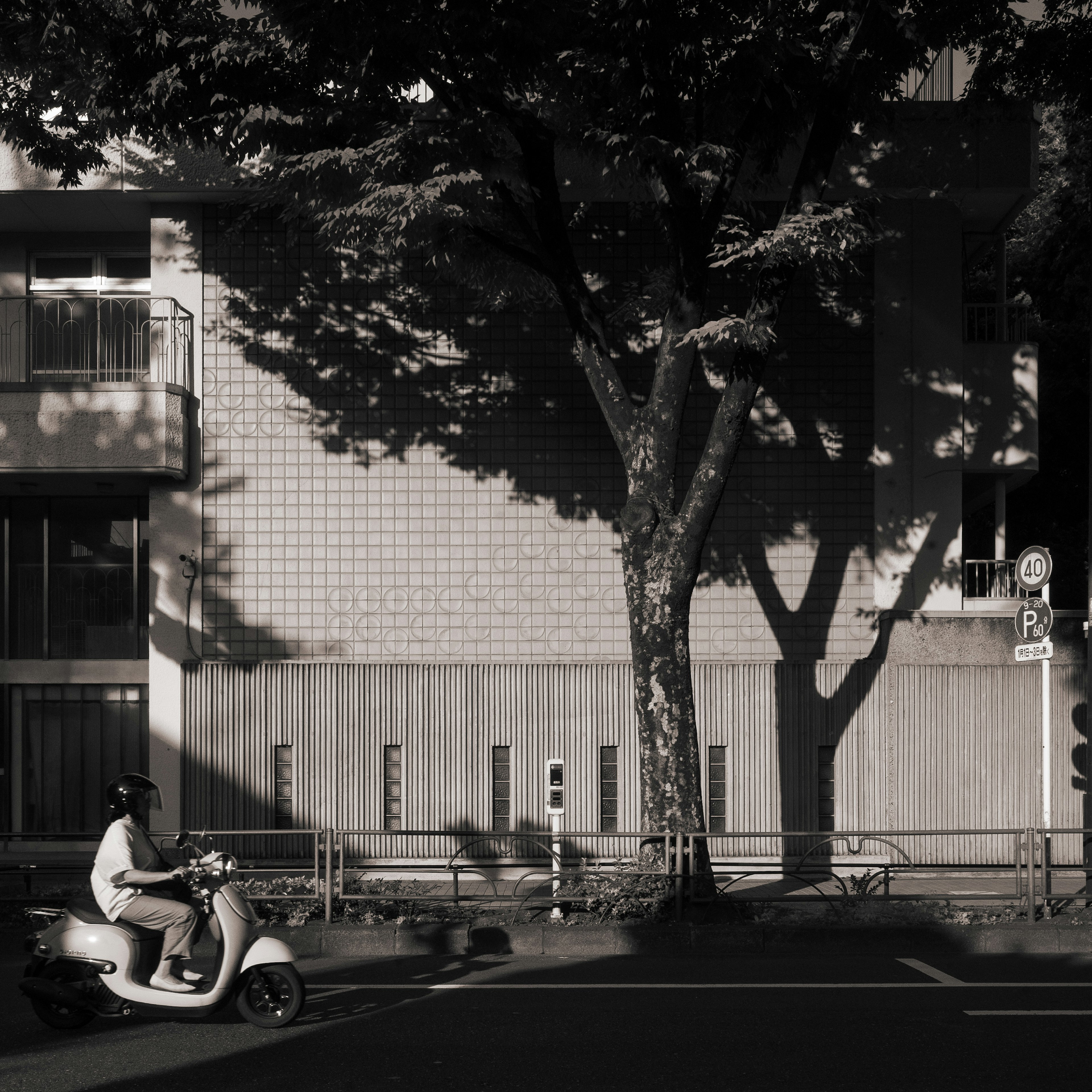 Scène de rue en noir et blanc avec une personne sur un scooter passant