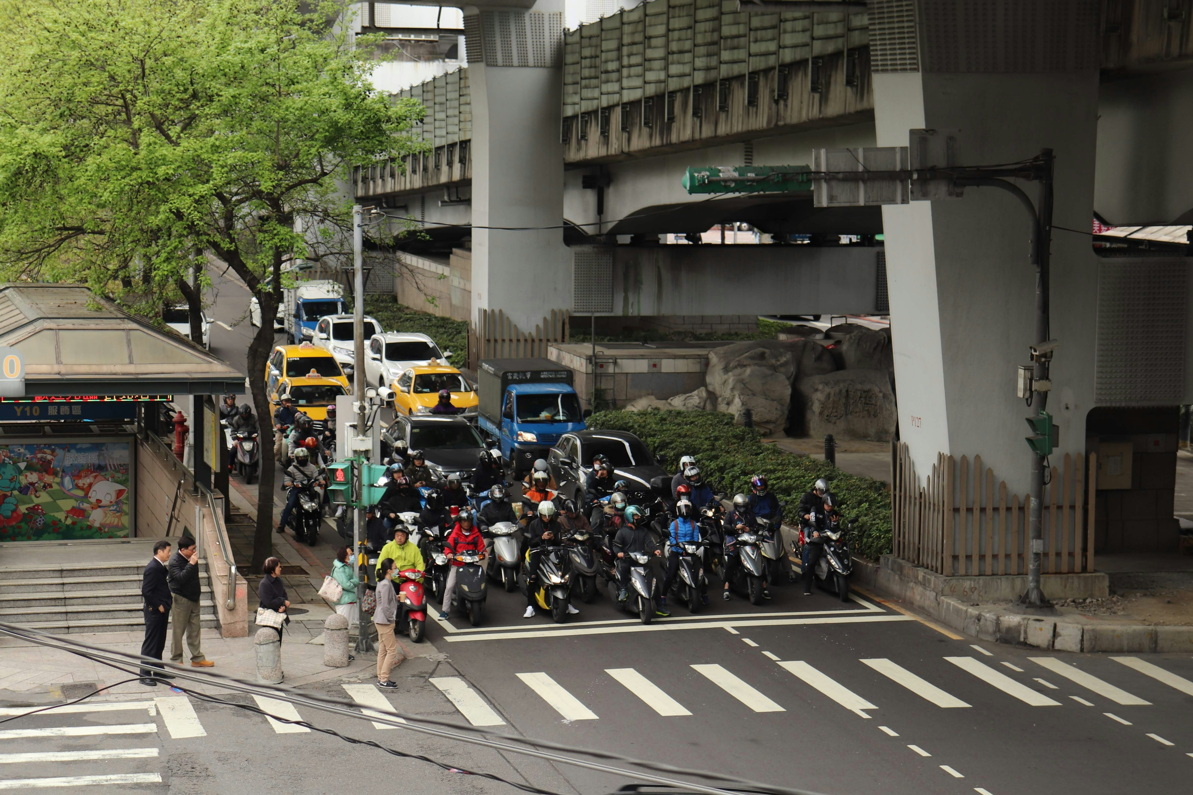 Traffic scene with motorcycles and cars under an elevated bridge