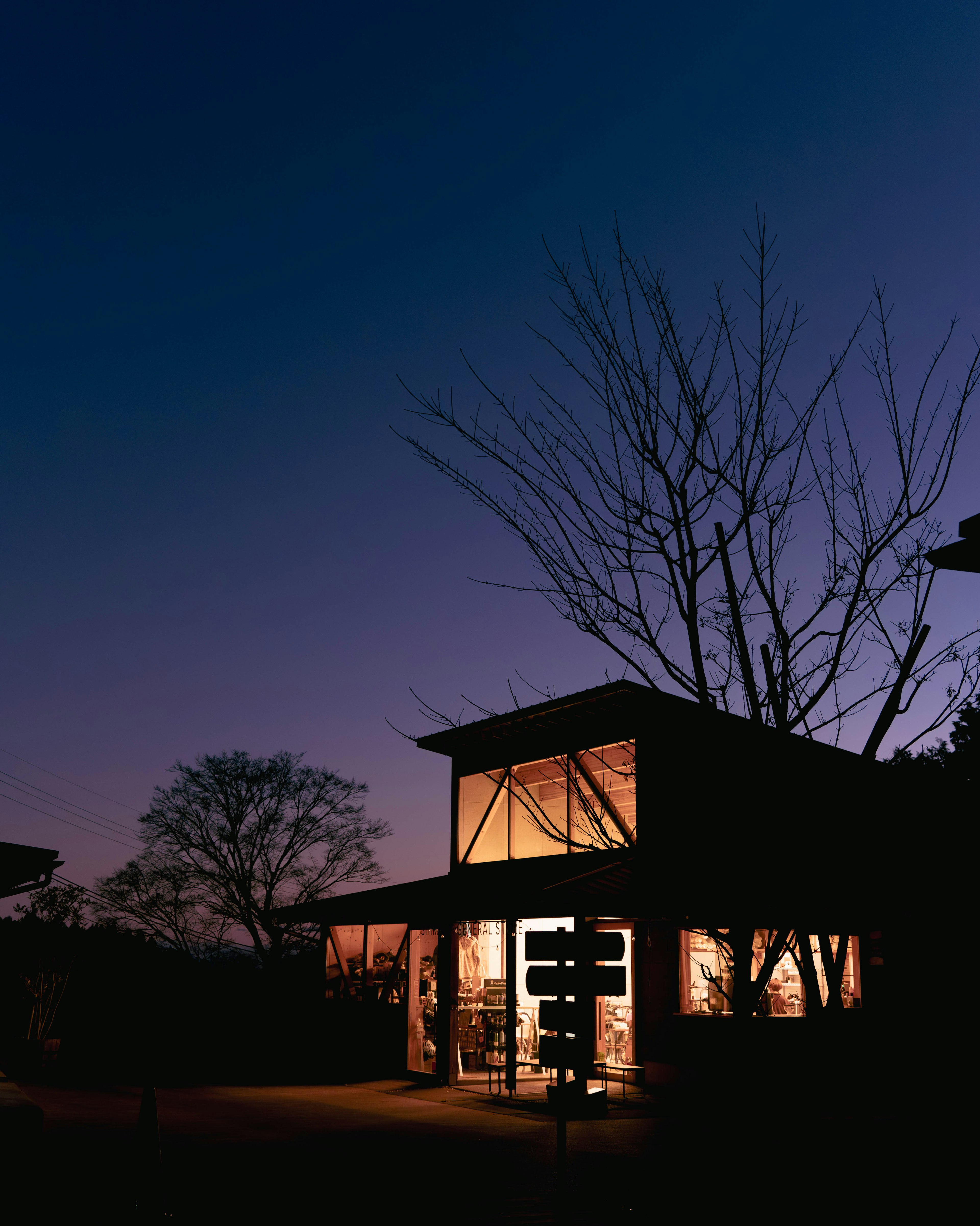 Modern house exterior under twilight with warm light glowing from windows