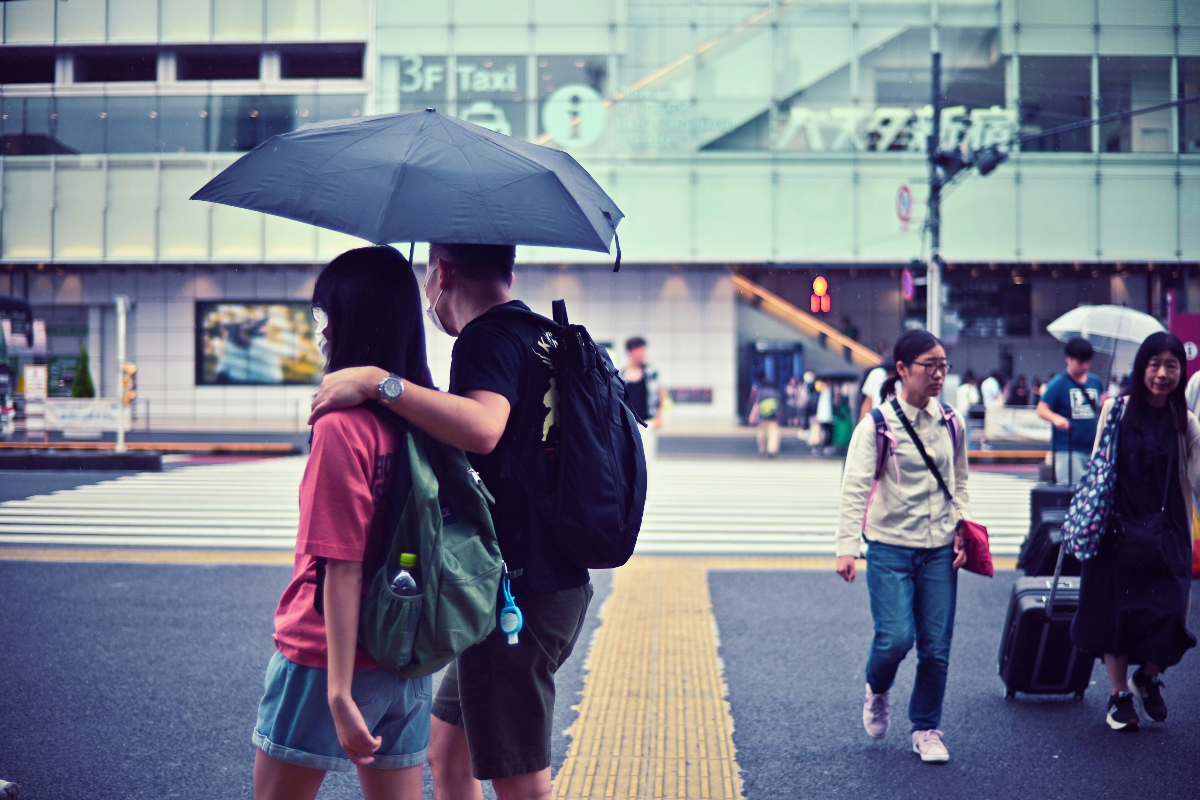 Couple partageant un parapluie à un passage piéton dans une ville