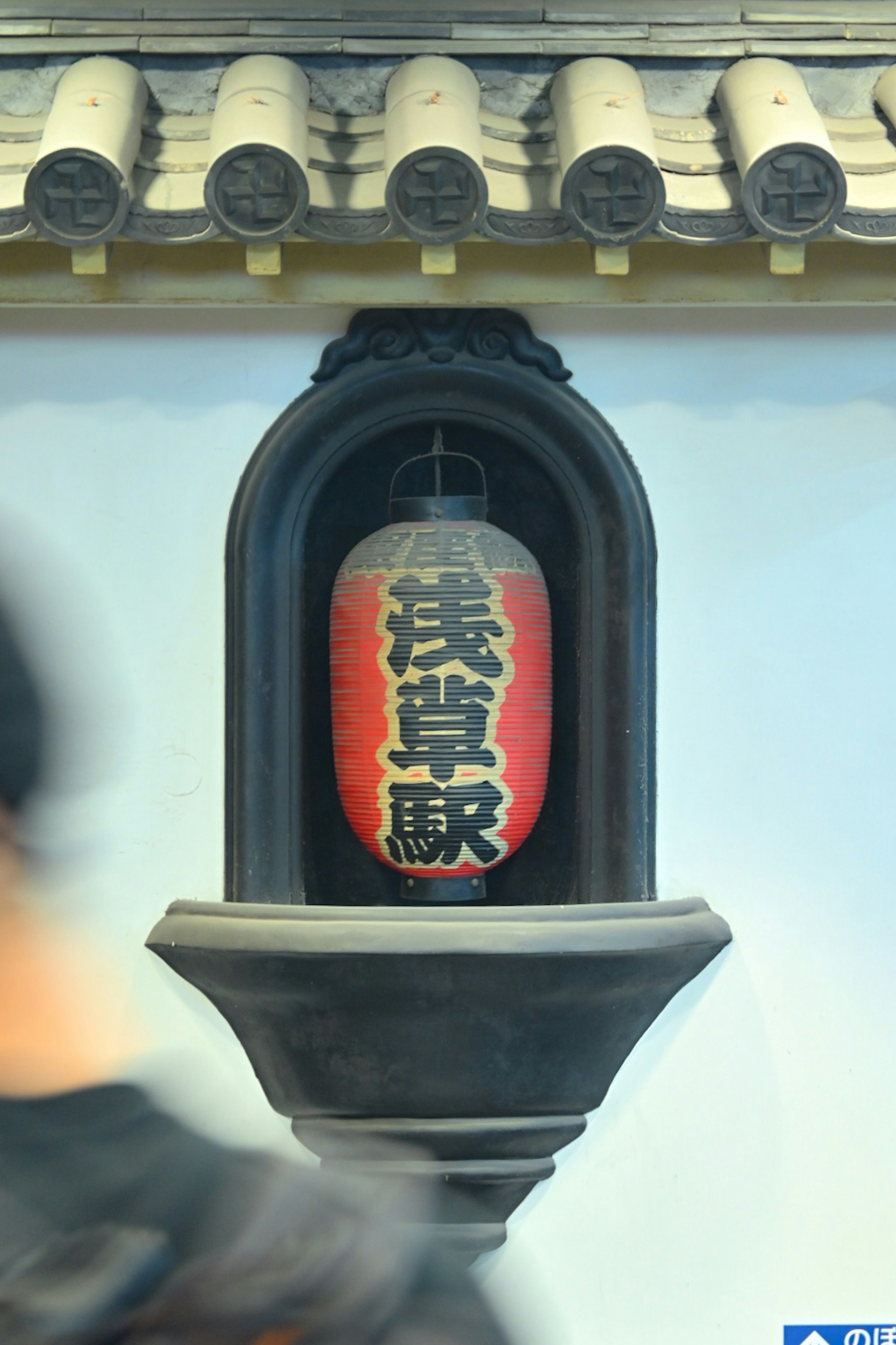 Una linterna roja con los caracteres de la estación Asakusa exhibida en una pared