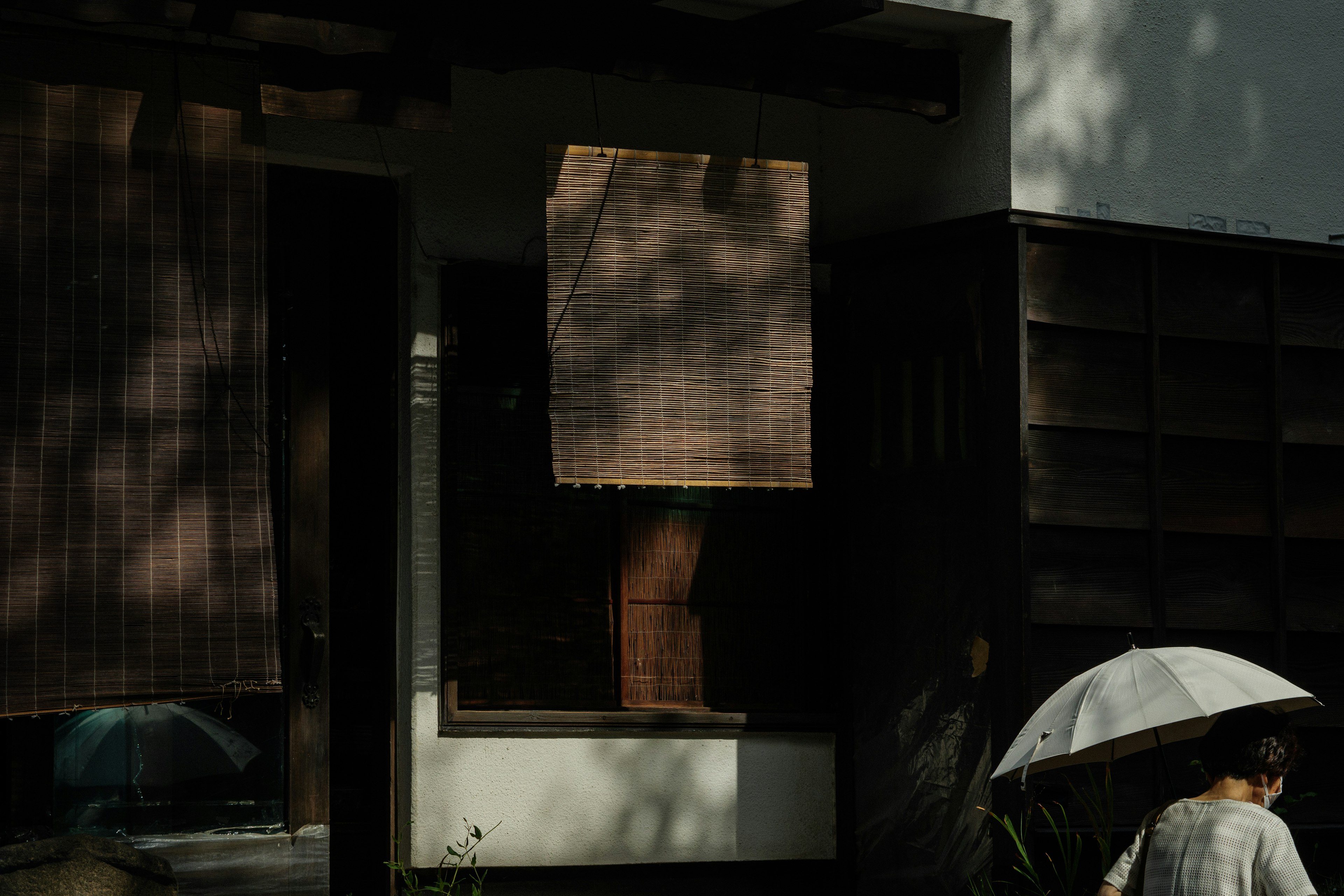 Extérieur d'un bâtiment moderne avec des ombres et une personne tenant un parapluie