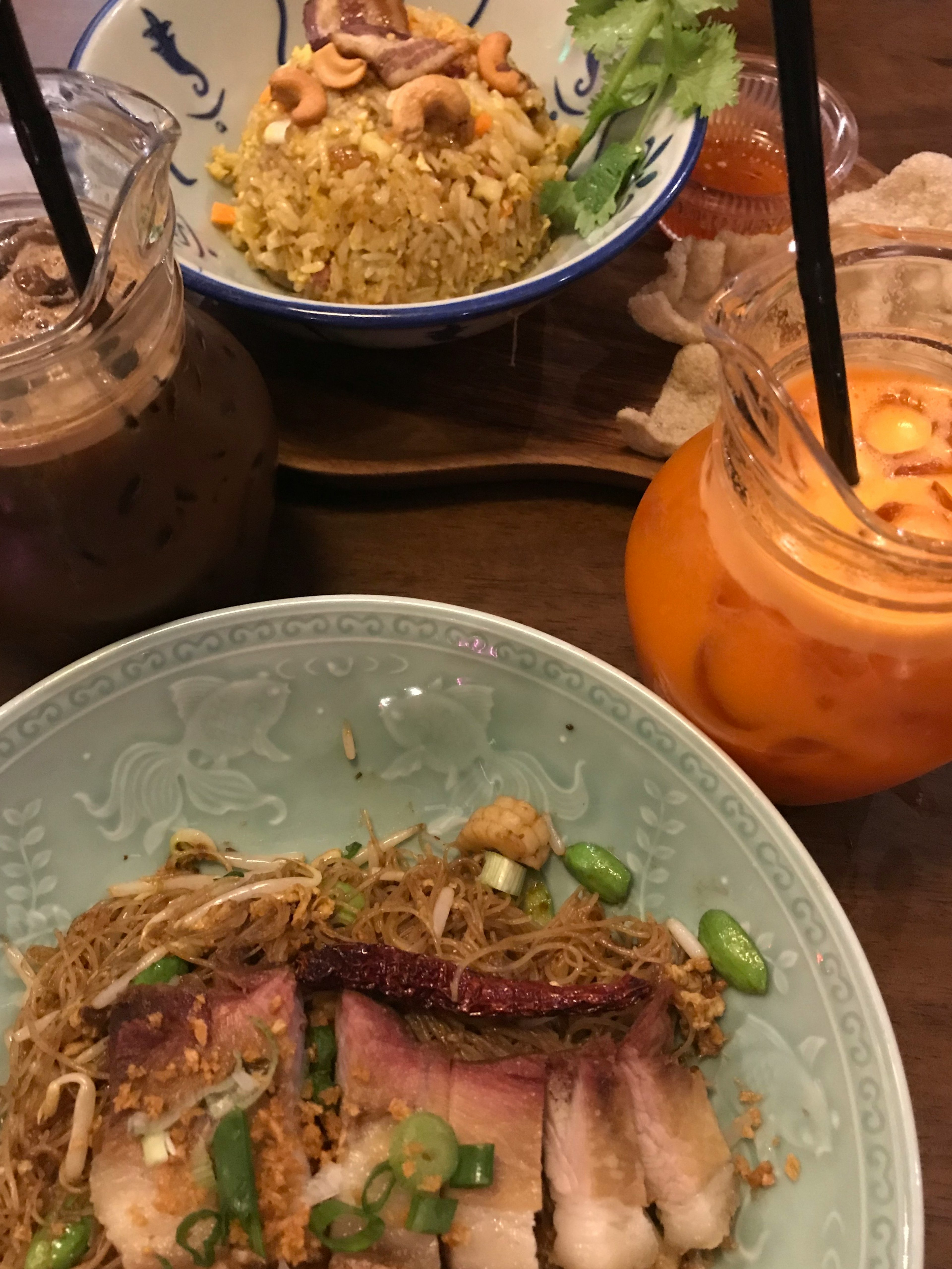 A table set with delicious dishes featuring fried noodles and drinks