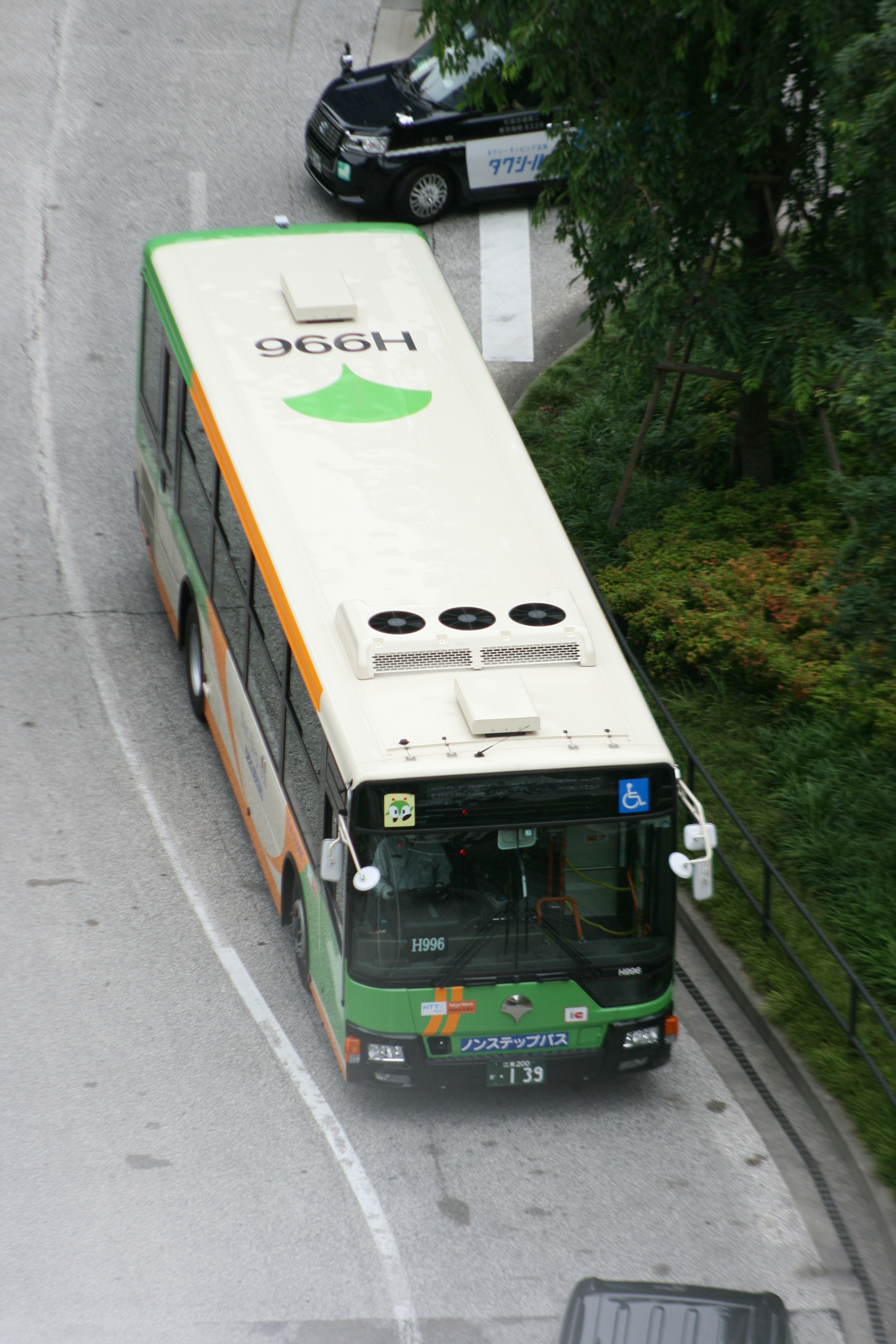 A green and orange bus navigating a curved road