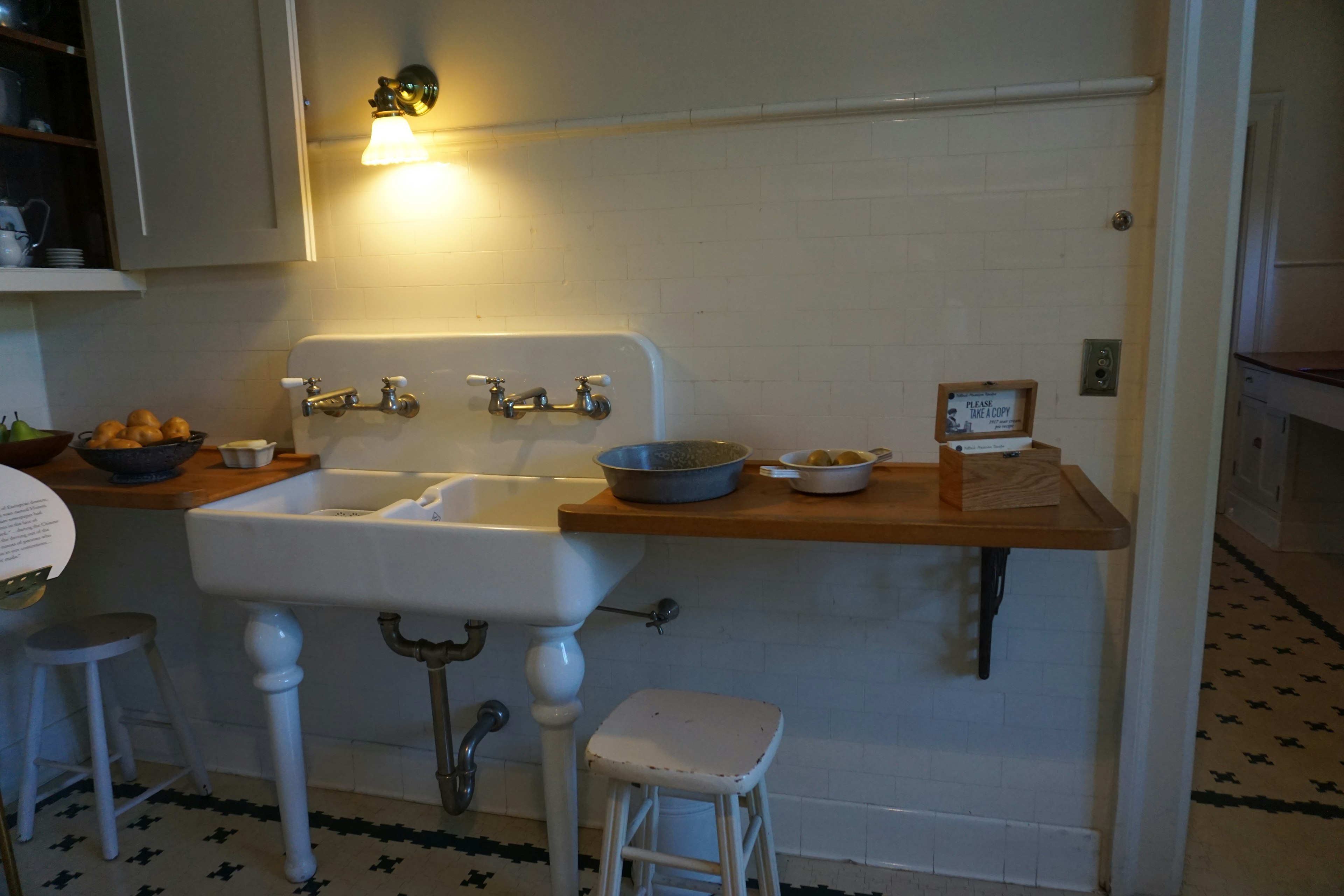 A corner of a simple kitchen featuring a white sink and wooden countertop