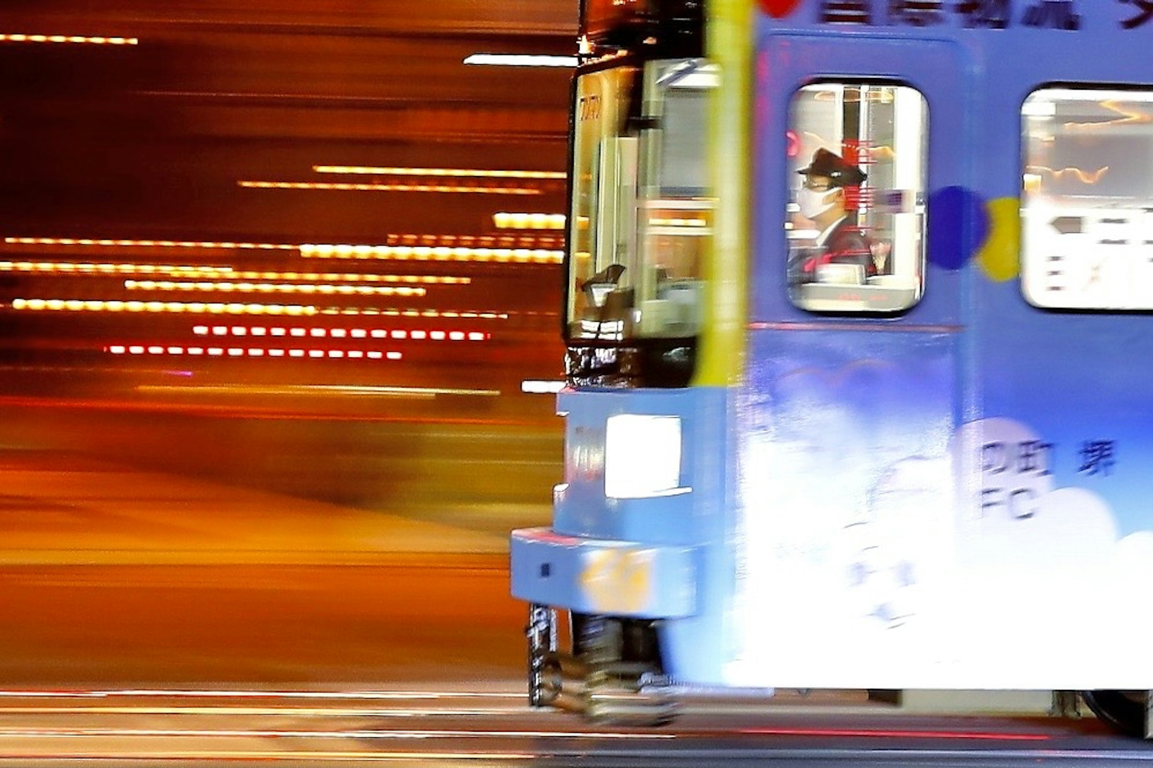 Kereta berwarna cerah melaju cepat melalui pemandangan malam dengan efek buram