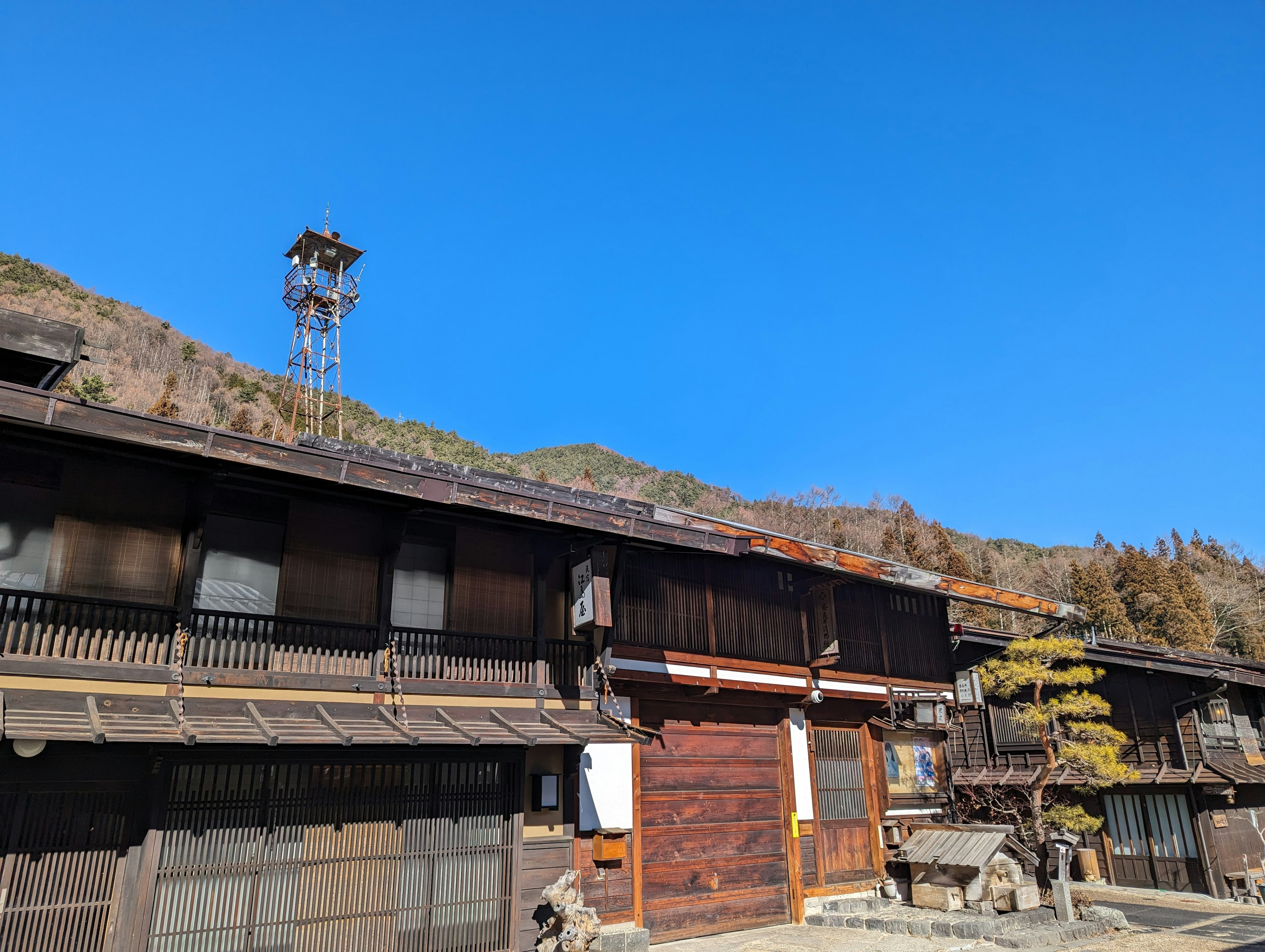 青空の下にある伝統的な木造建築と山の風景