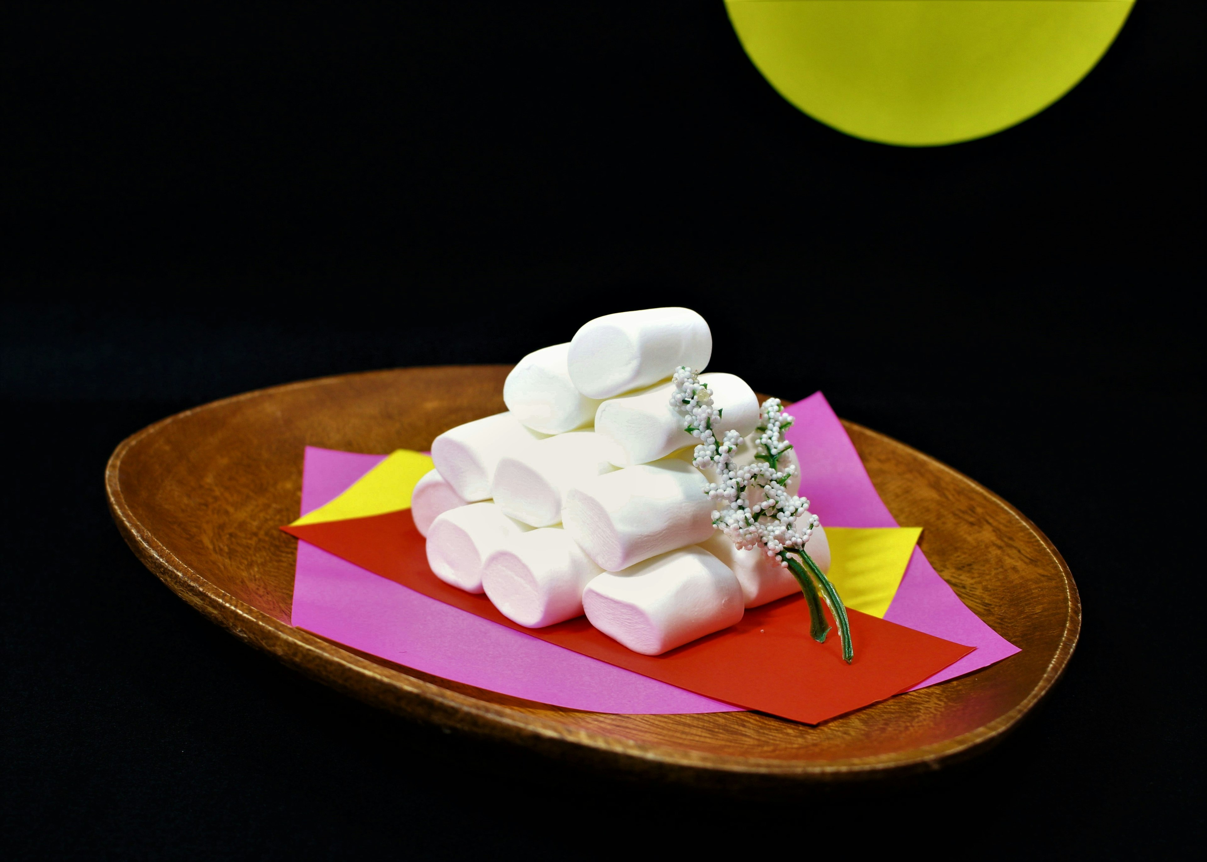 Sekumpulan marshmallow putih di atas latar belakang kertas berwarna dengan hiasan bunga