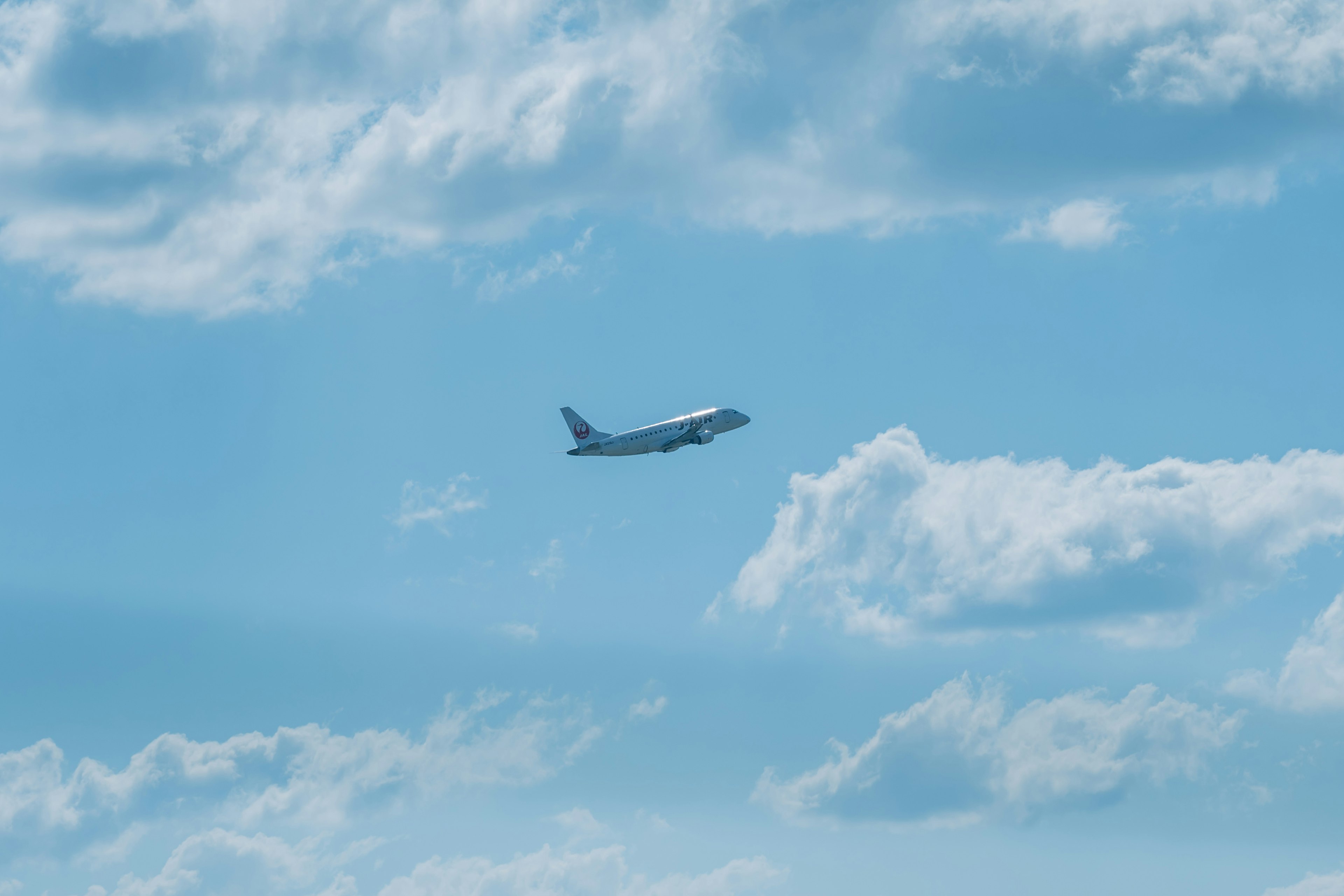 Un avión volando en un cielo azul con nubes esponjosas